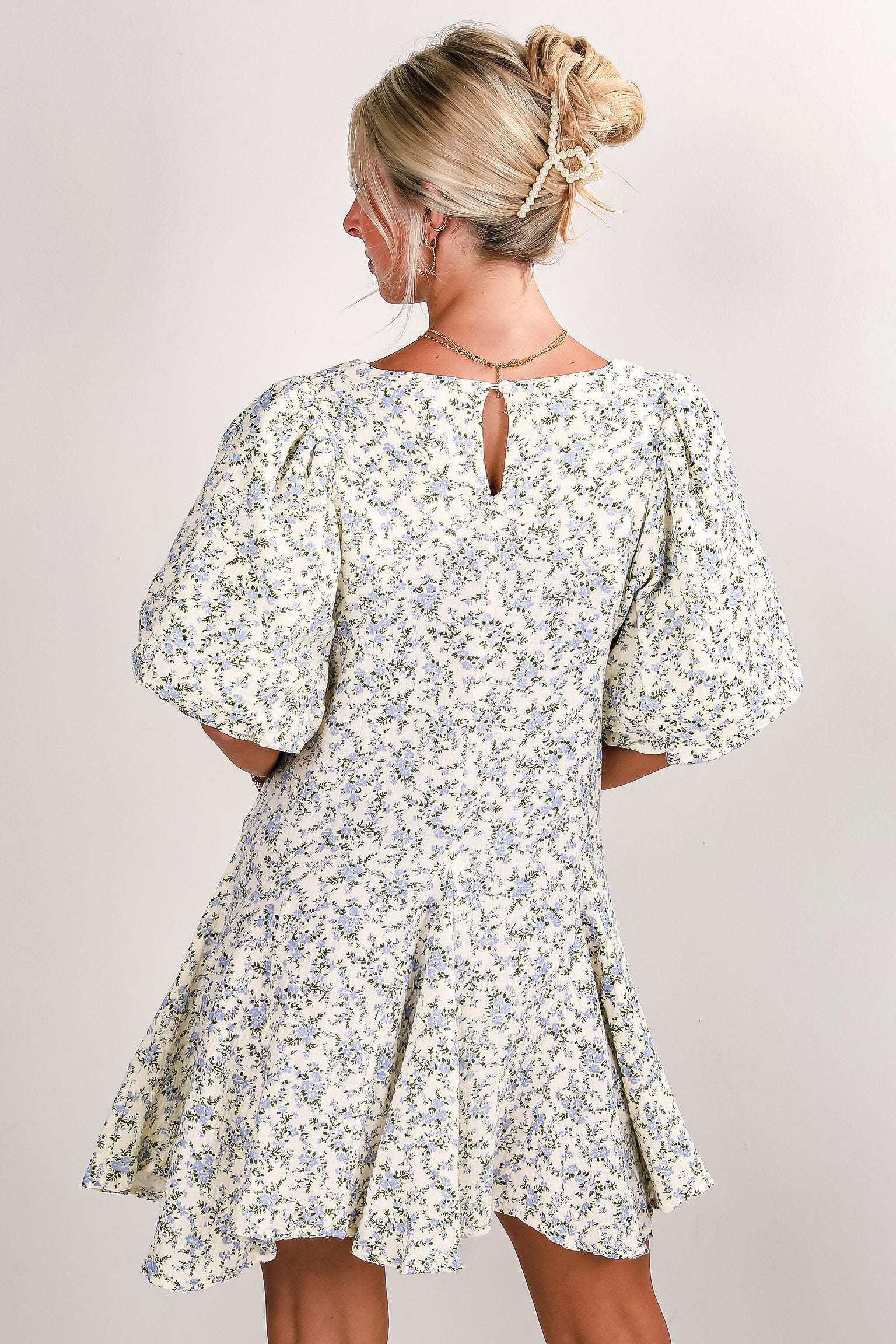 Woman wearing a floral dress against a plain background