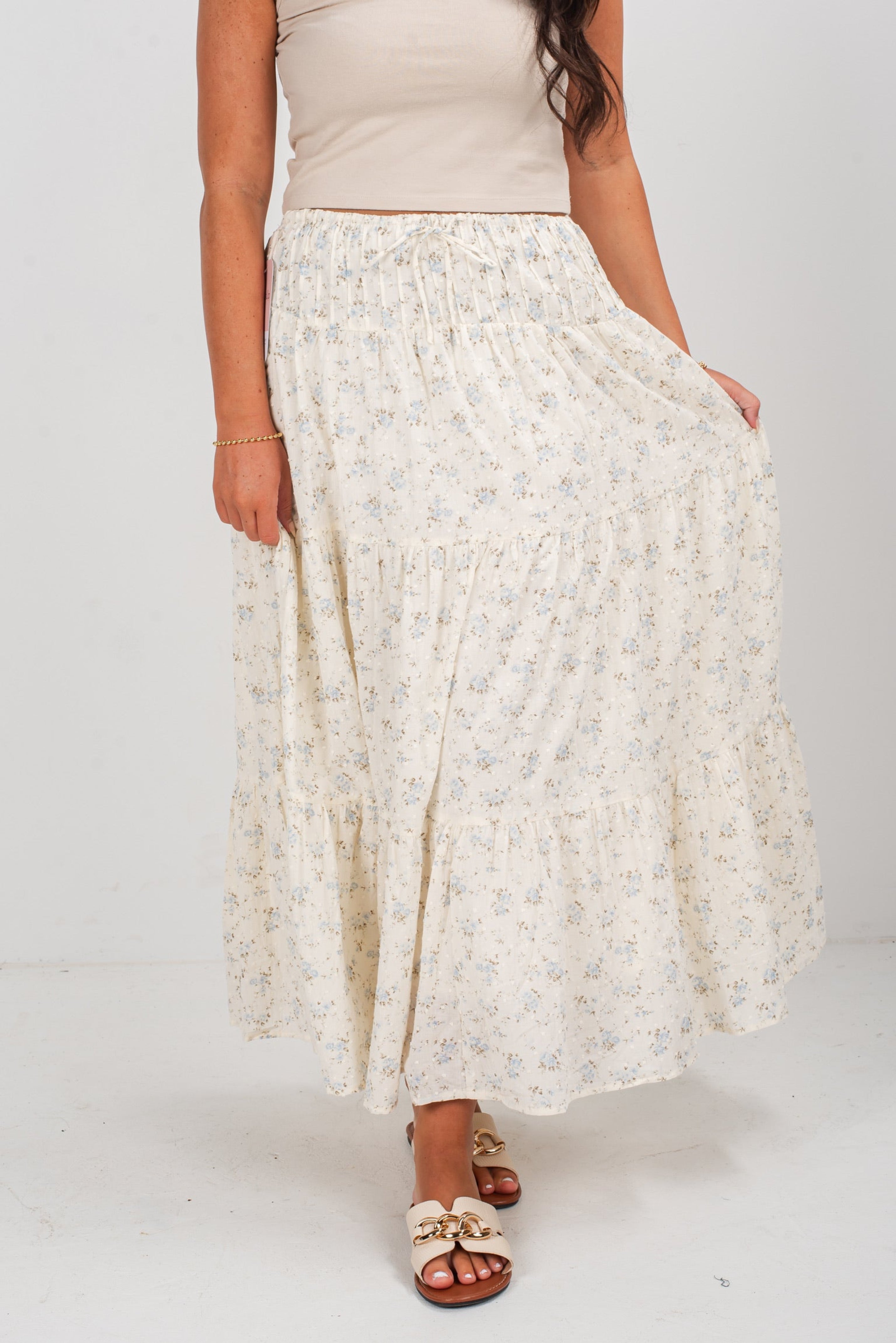 Person wearing a long, light-colored floral skirt on a white background