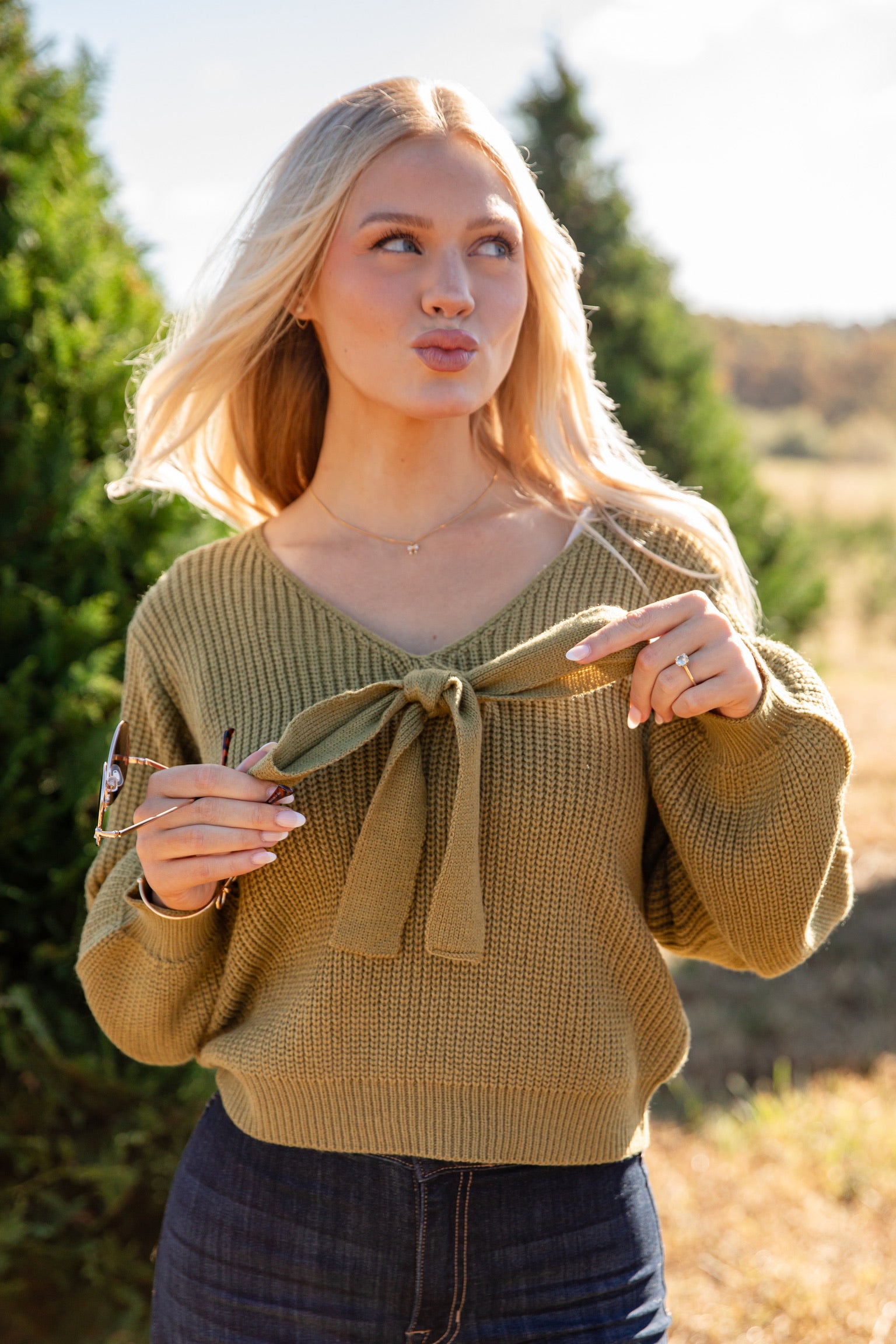Woman wearing a green sweater with a bow detail outdoors