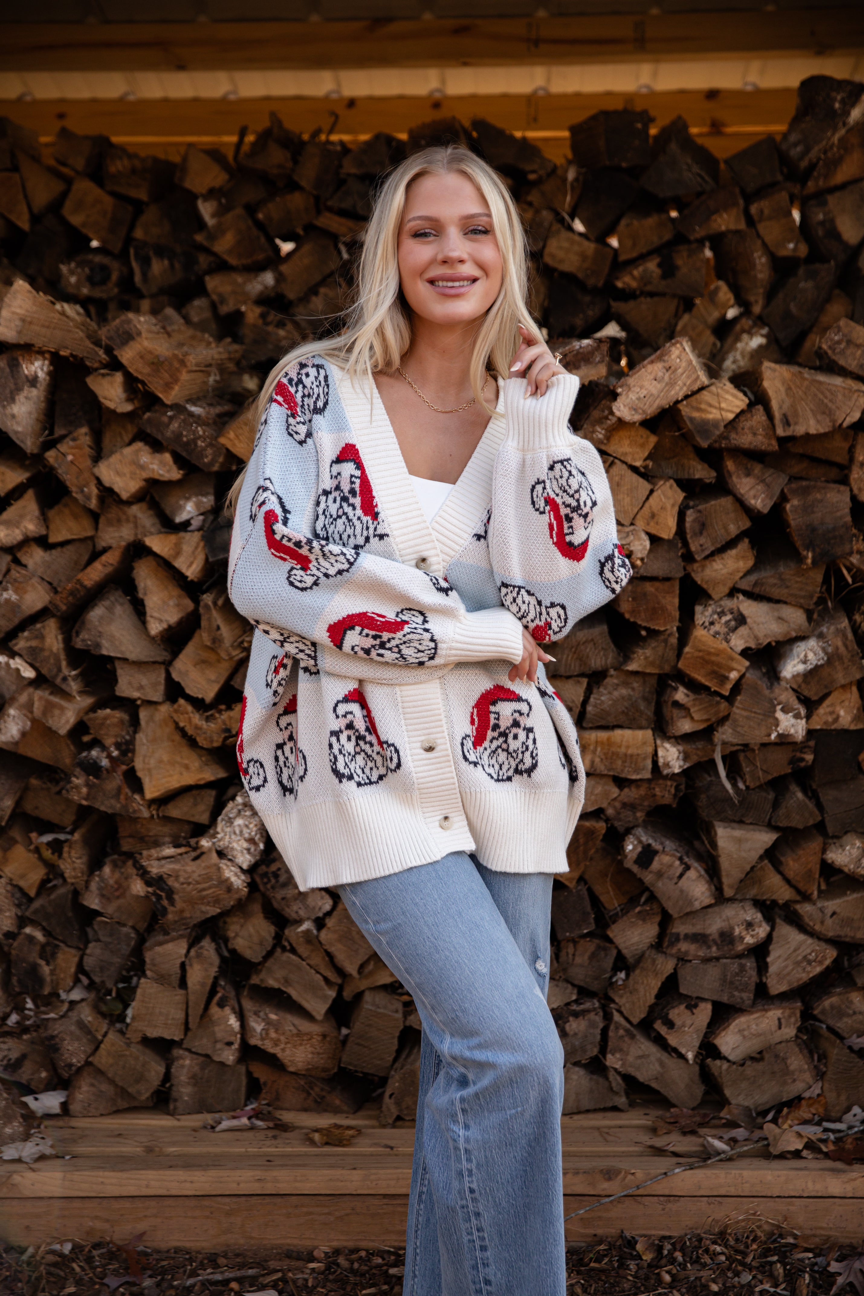 Woman wearing a patterned cardigan standing in front of stacked wood