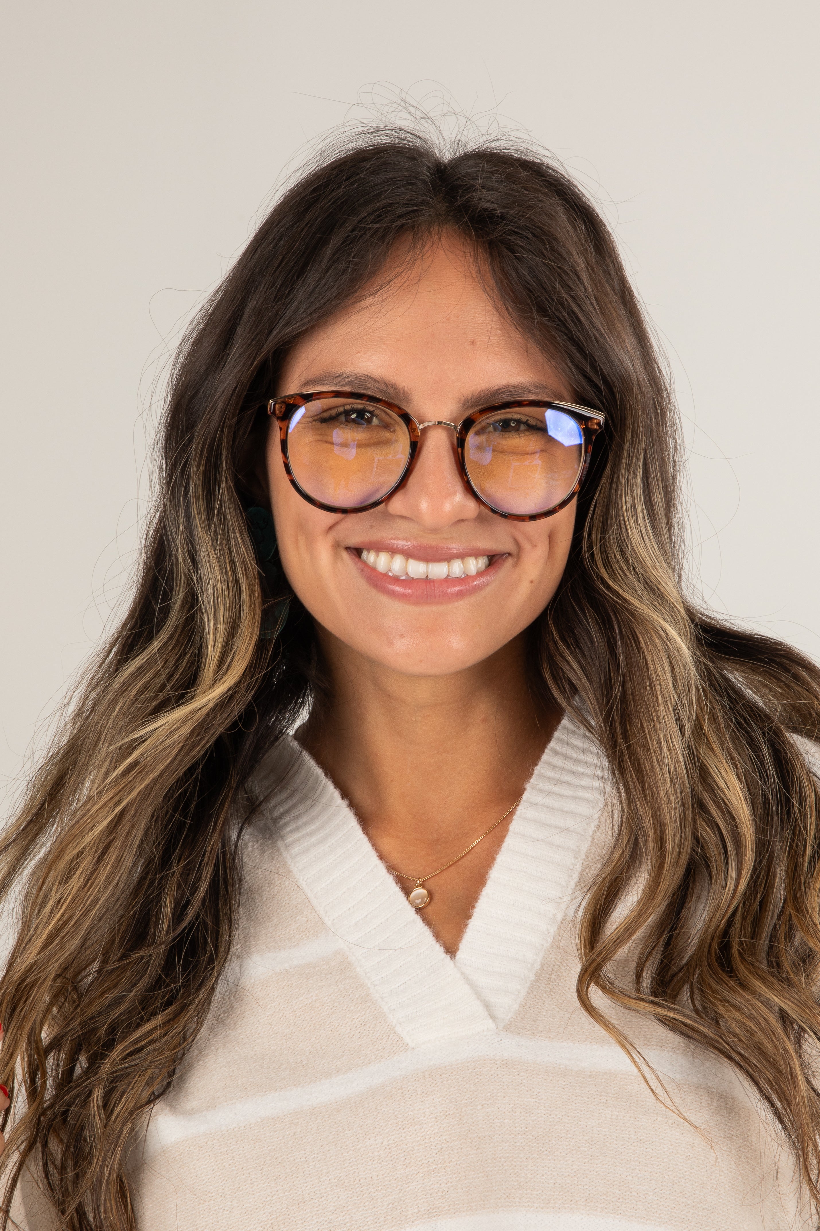 Woman wearing glasses and a beige sweater against a plain background