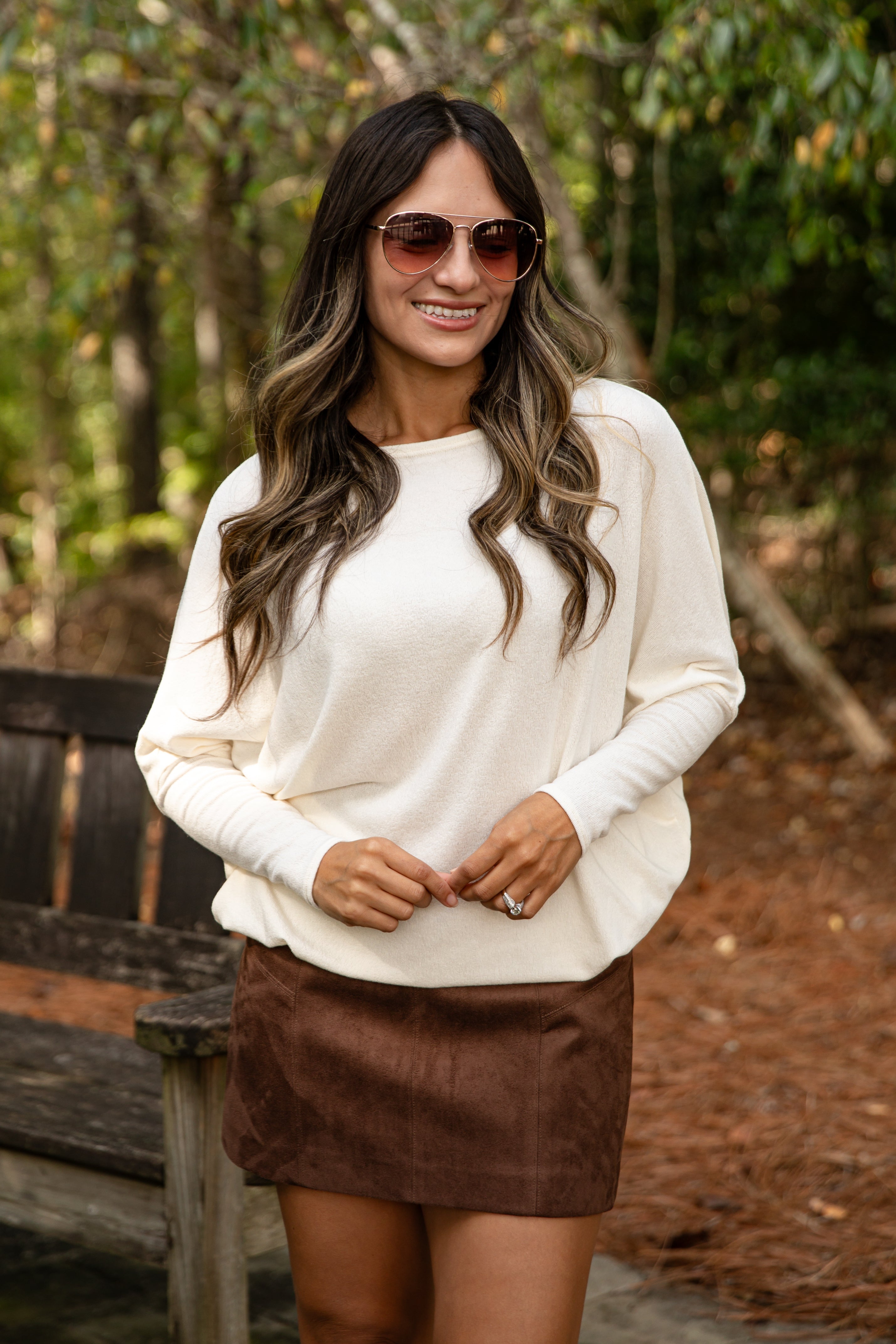 Woman wearing a white sweater and brown skirt outdoors