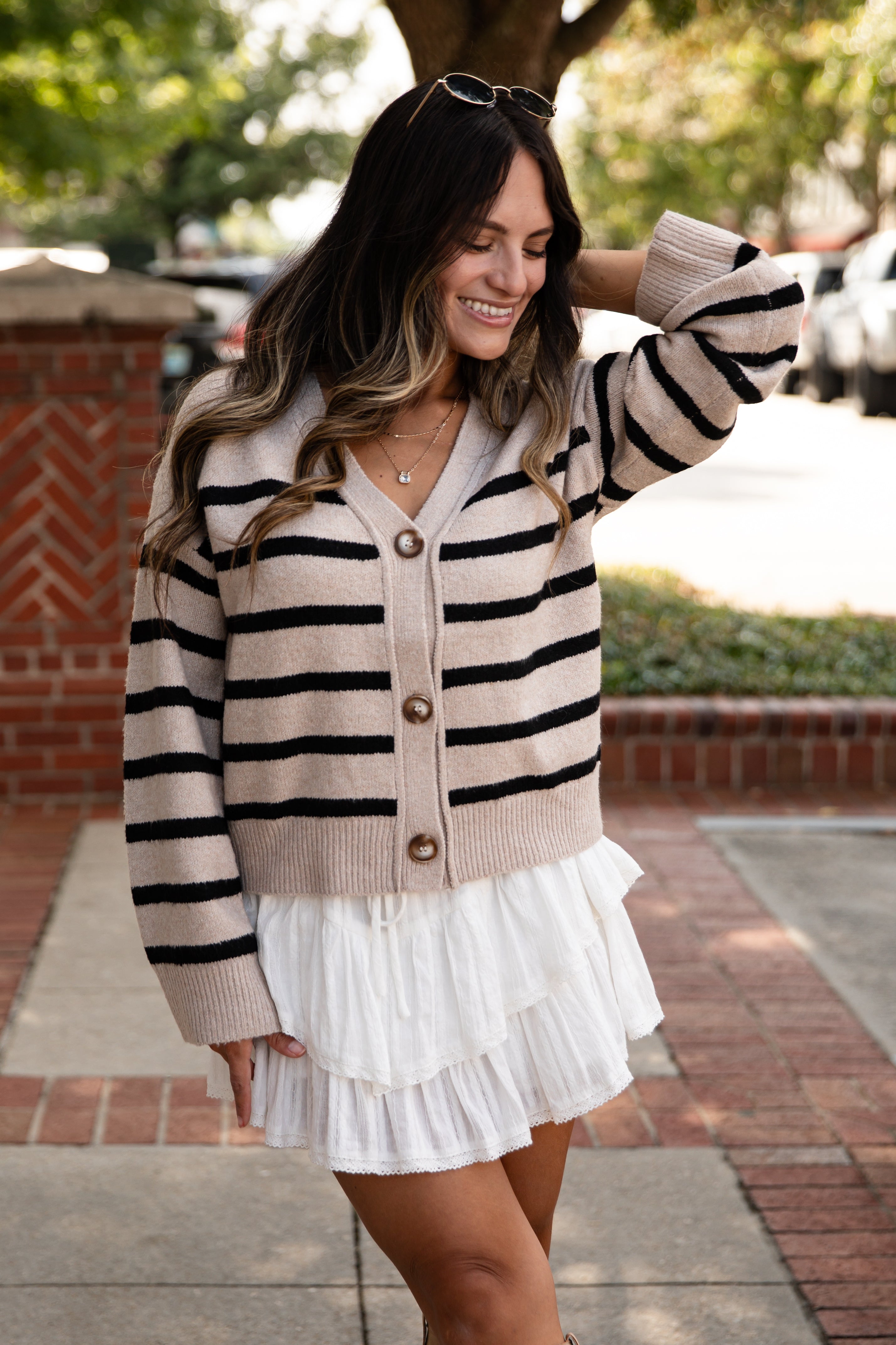 Woman wearing a striped cardigan and white skirt outdoors