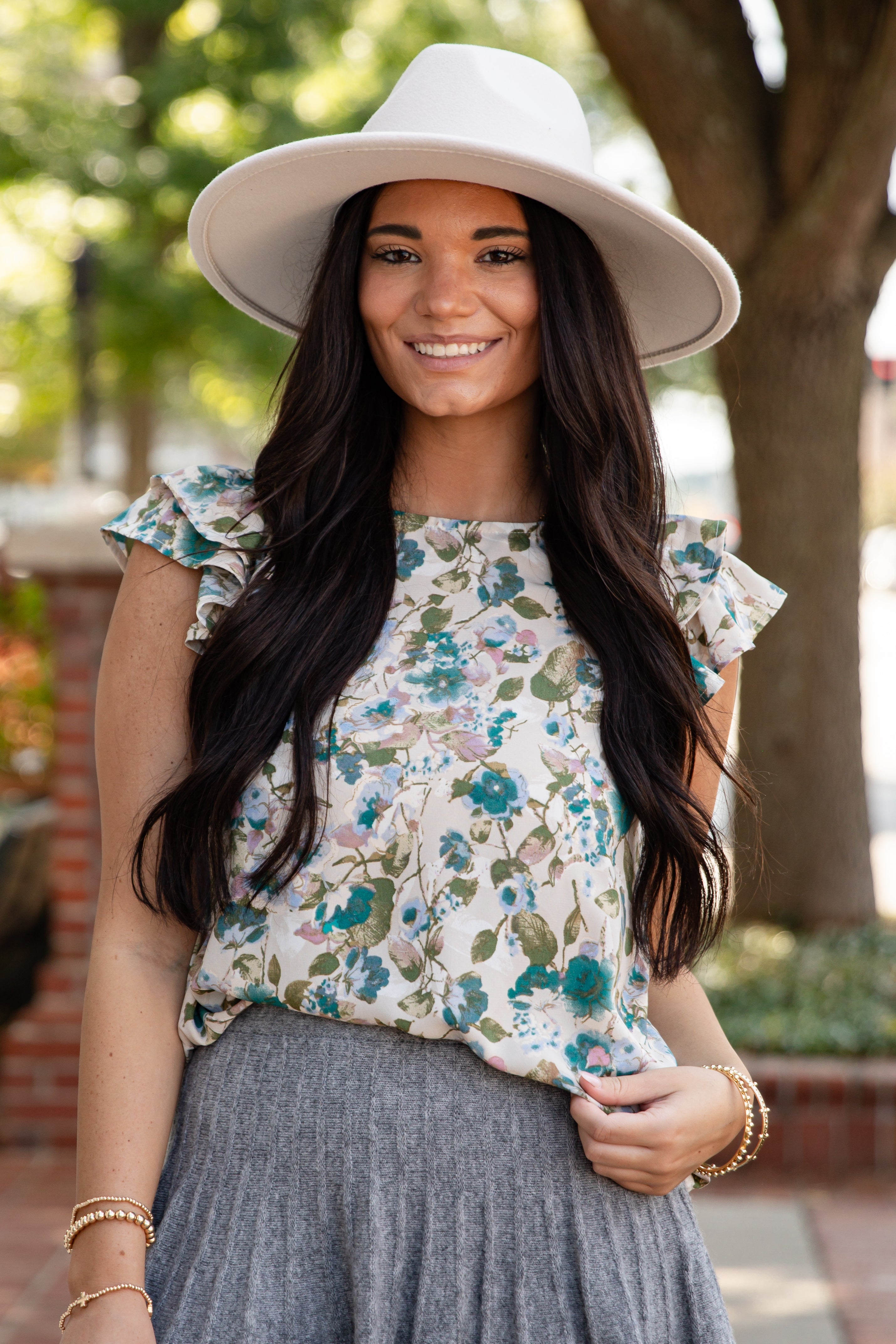 Woman wearing a floral top and white hat outdoors