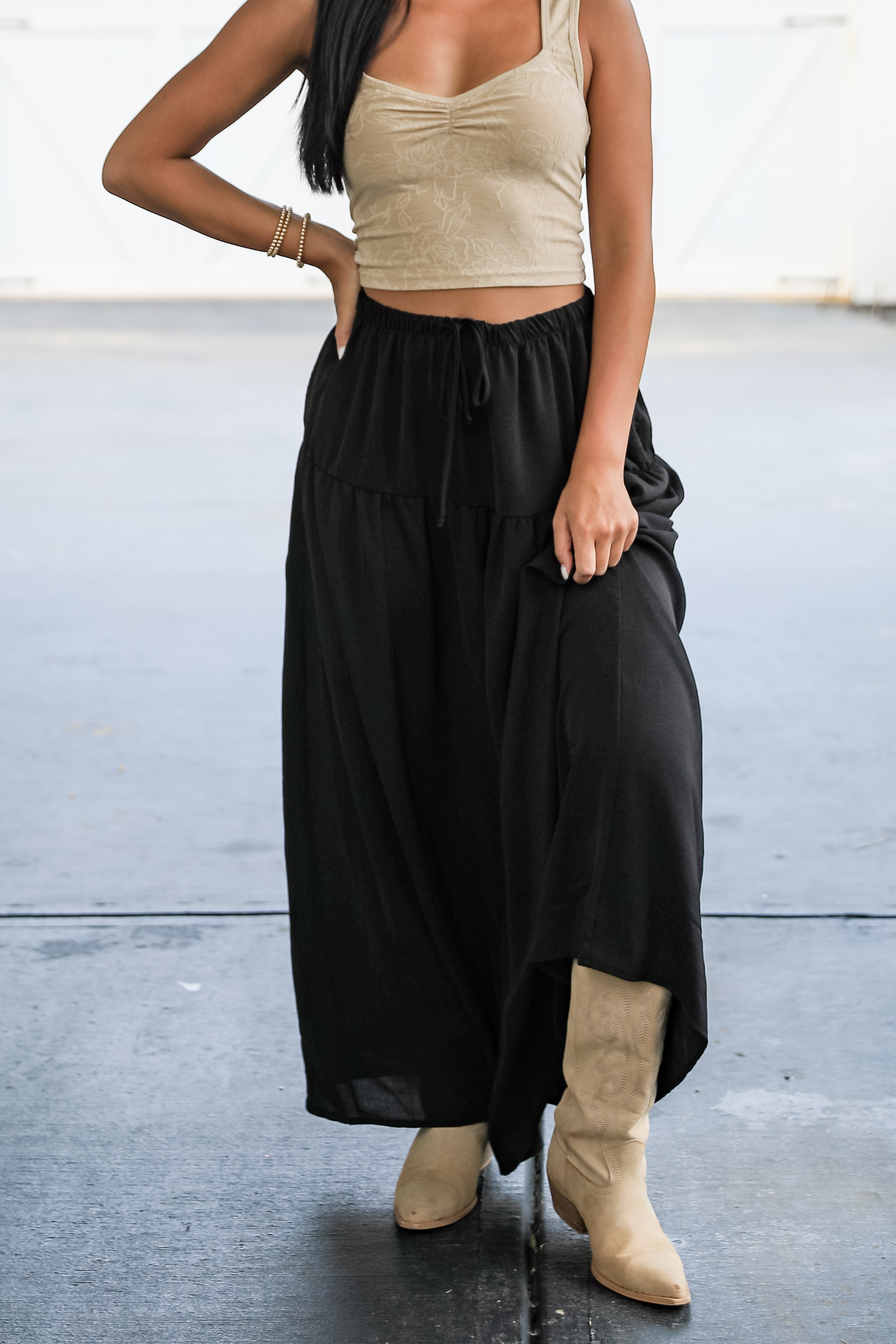 Person wearing a beige top and black wide-leg pants with beige boots on a light background