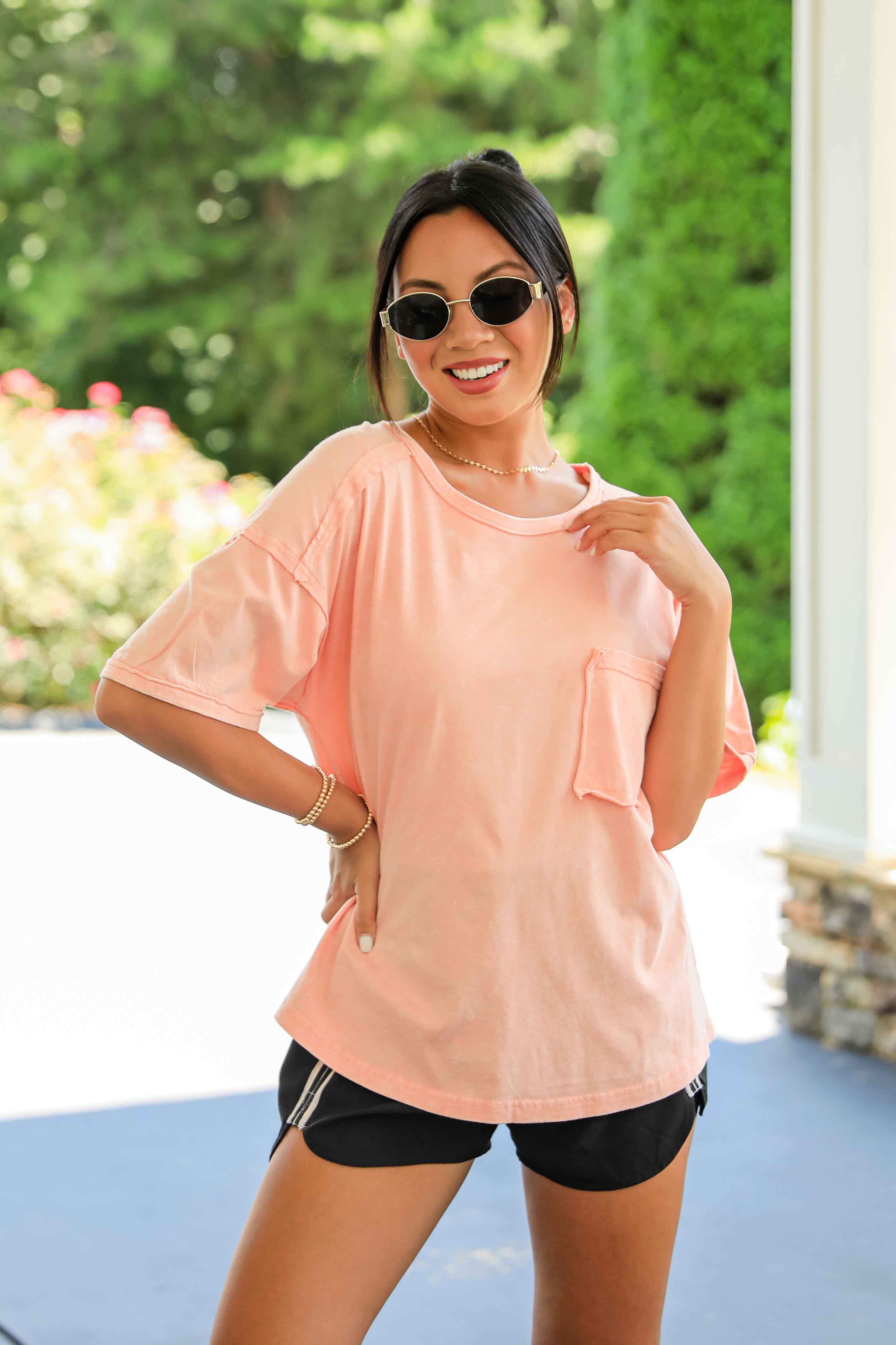 Woman wearing a peach-colored shirt and black shorts outdoors