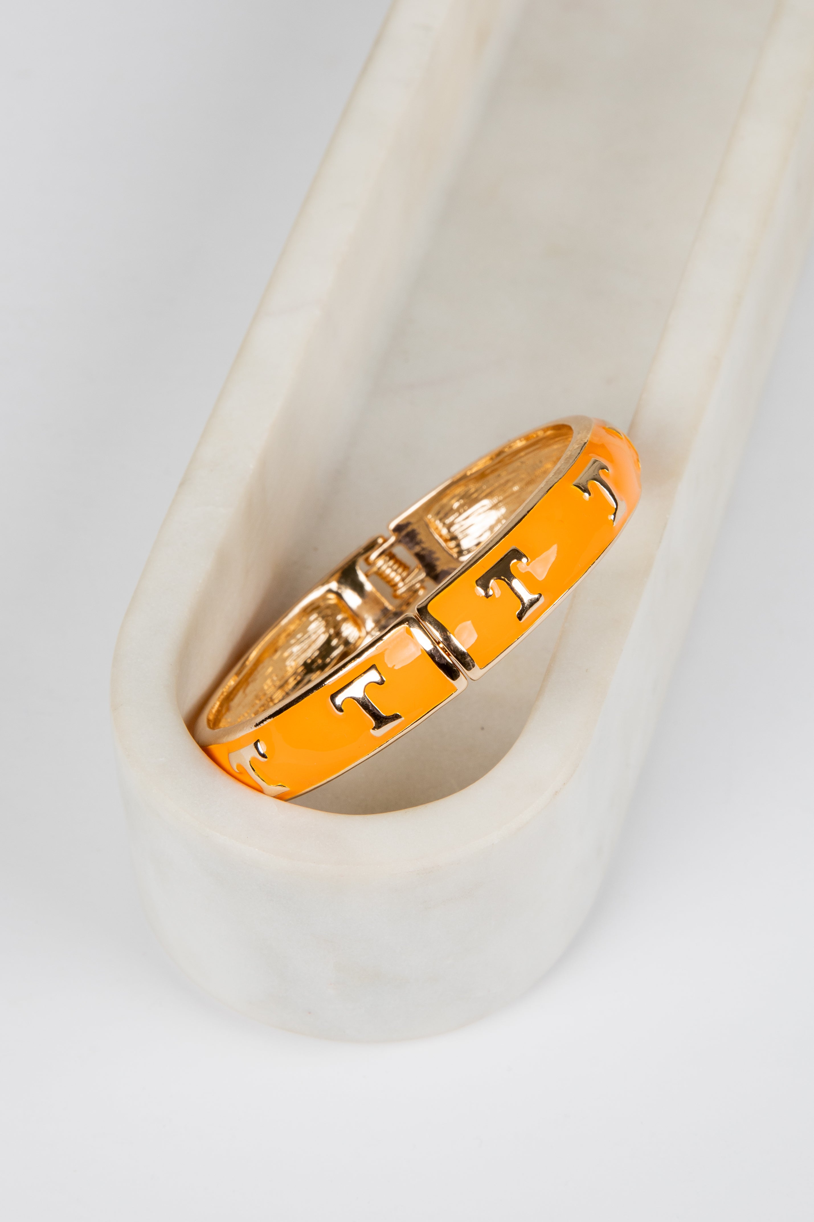 Gold and orange ring with lettering on a white surface