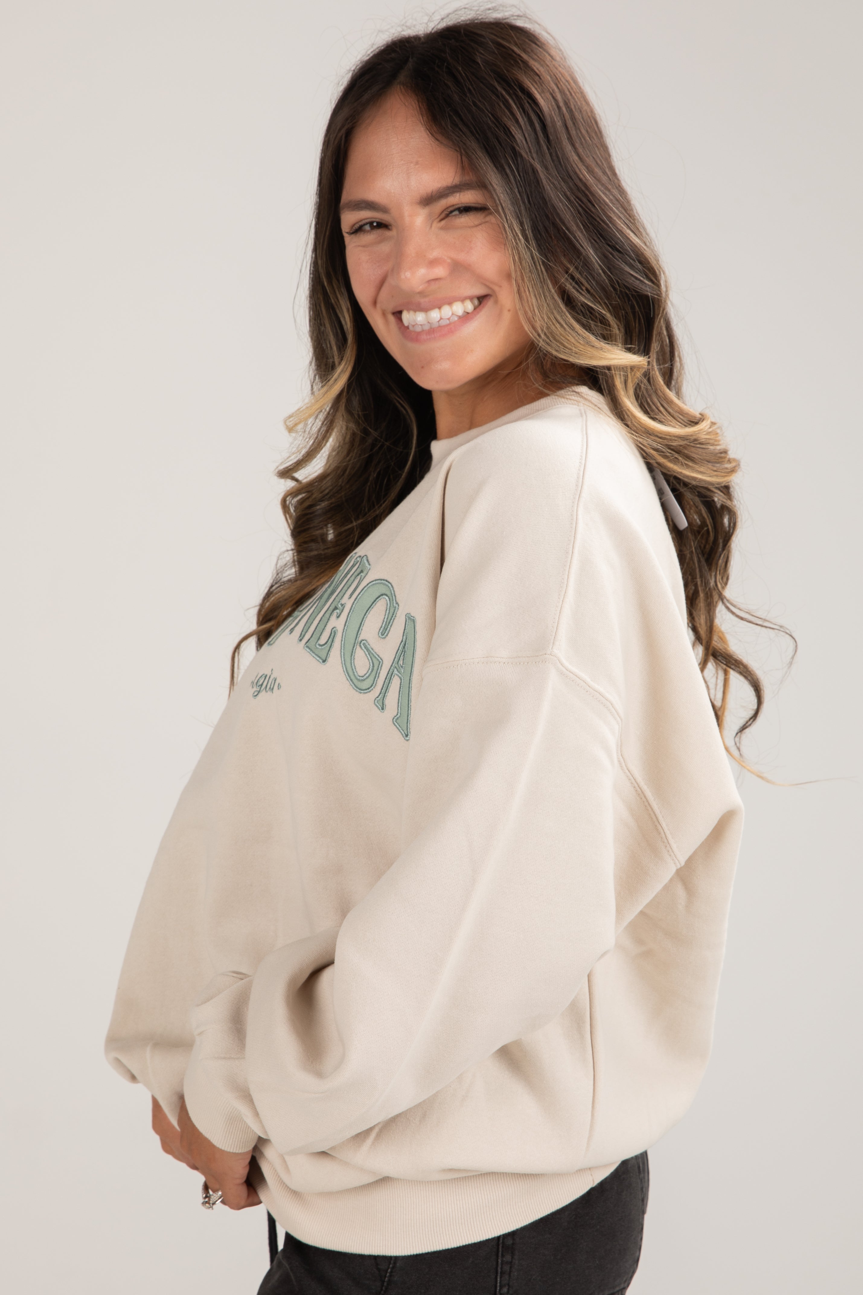 Woman wearing a beige sweatshirt with text on a plain background