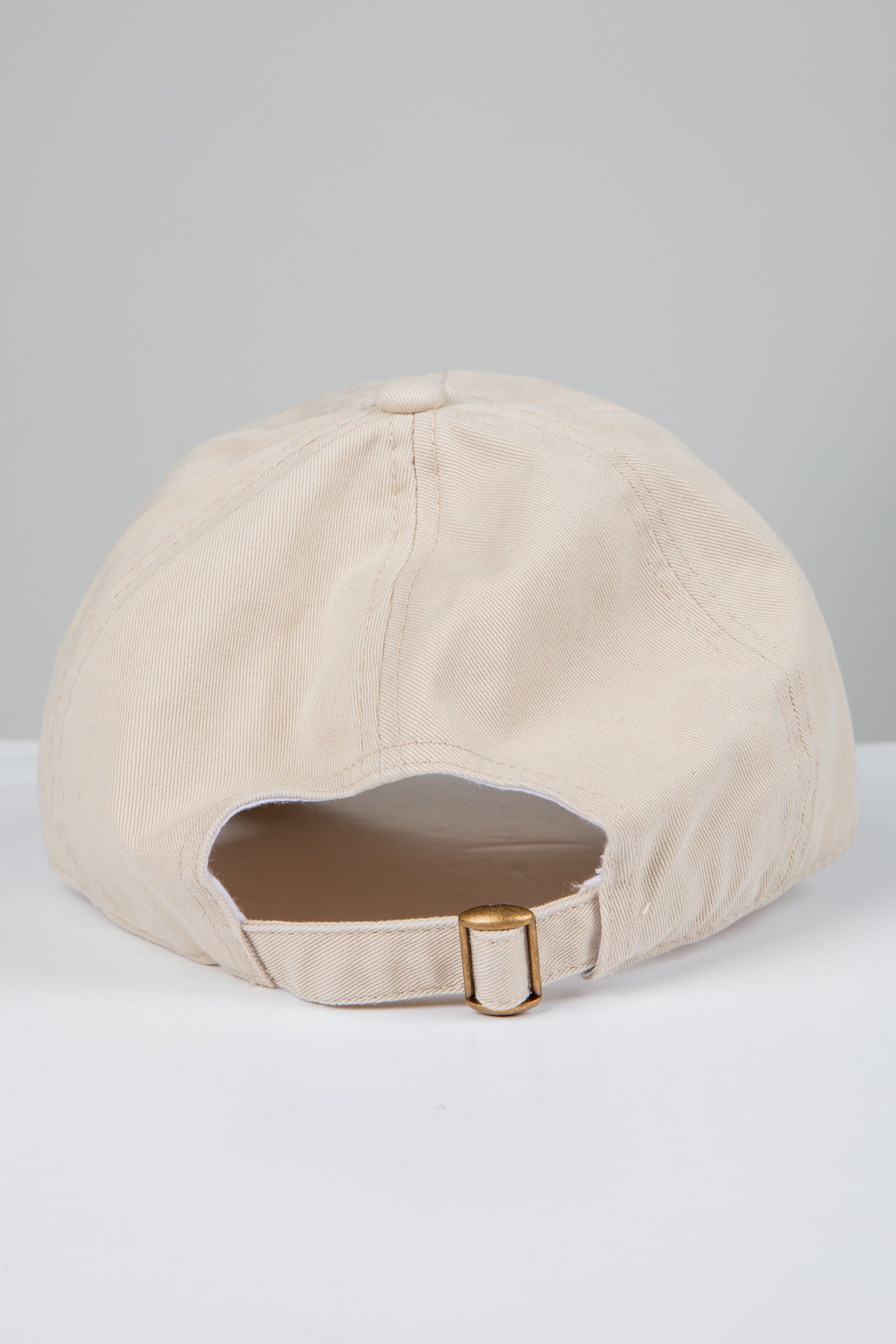 Beige baseball cap with brown patch on a light gray background