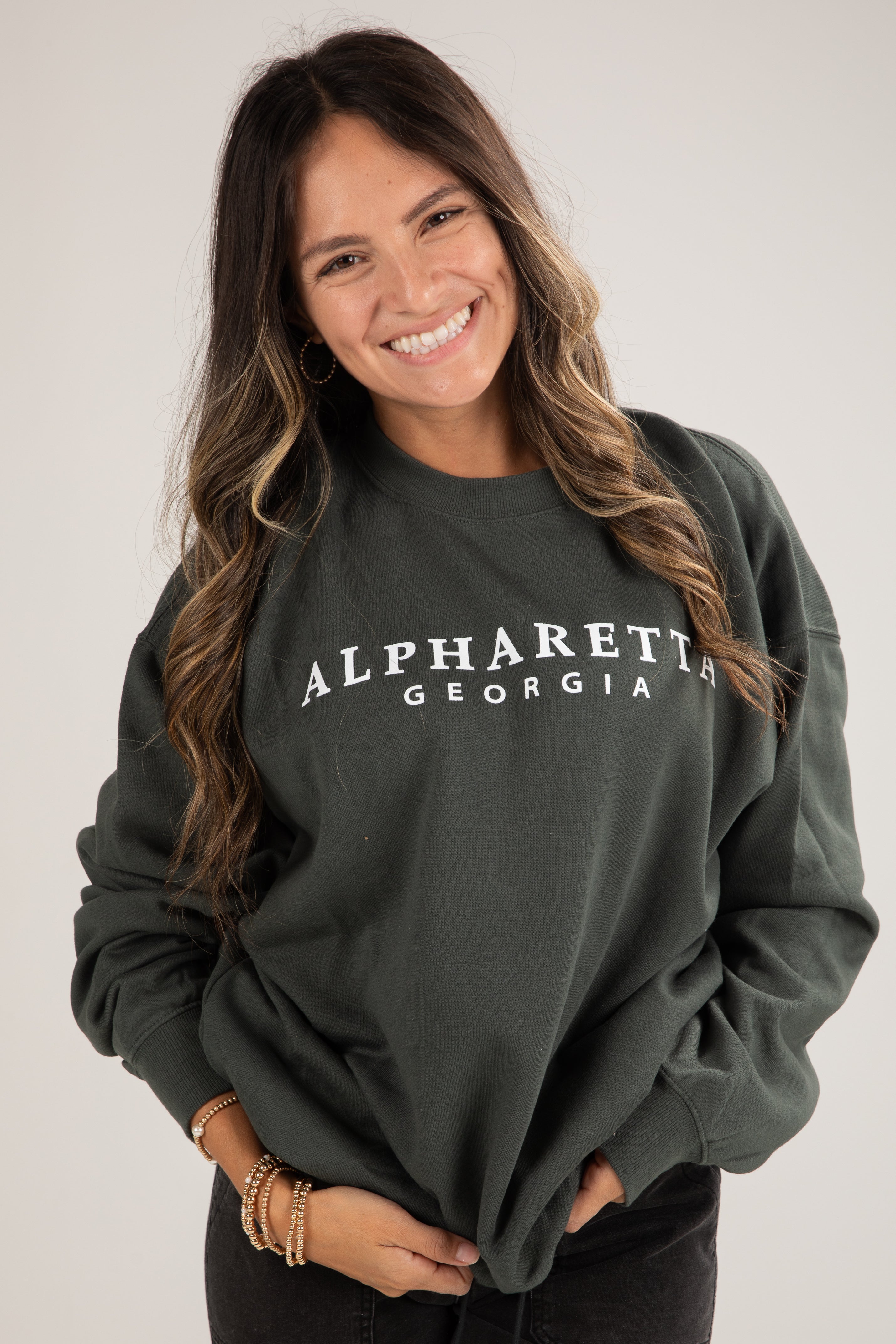 Woman wearing a dark green sweatshirt with &