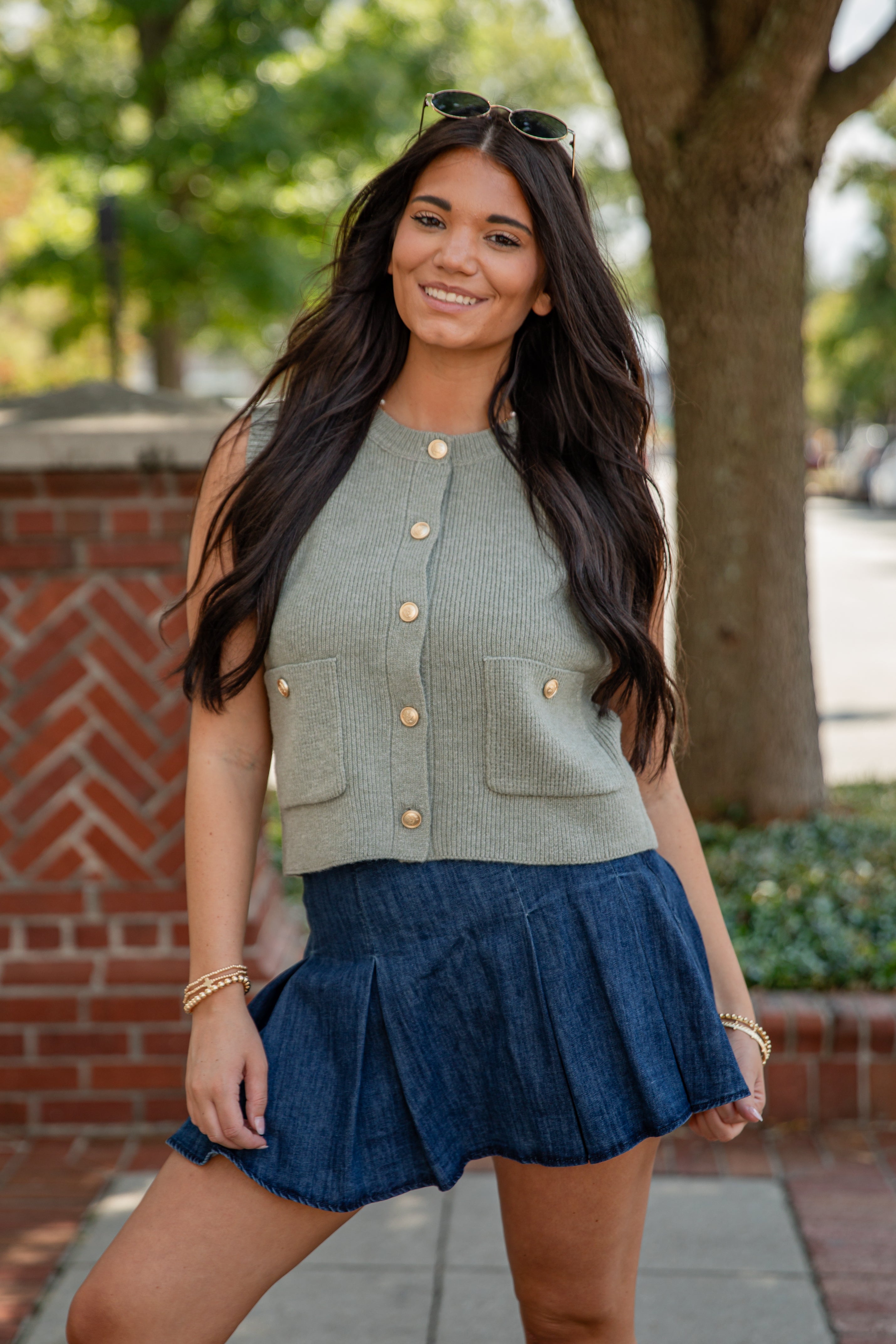Woman wearing a green cardigan and blue skirt outdoors