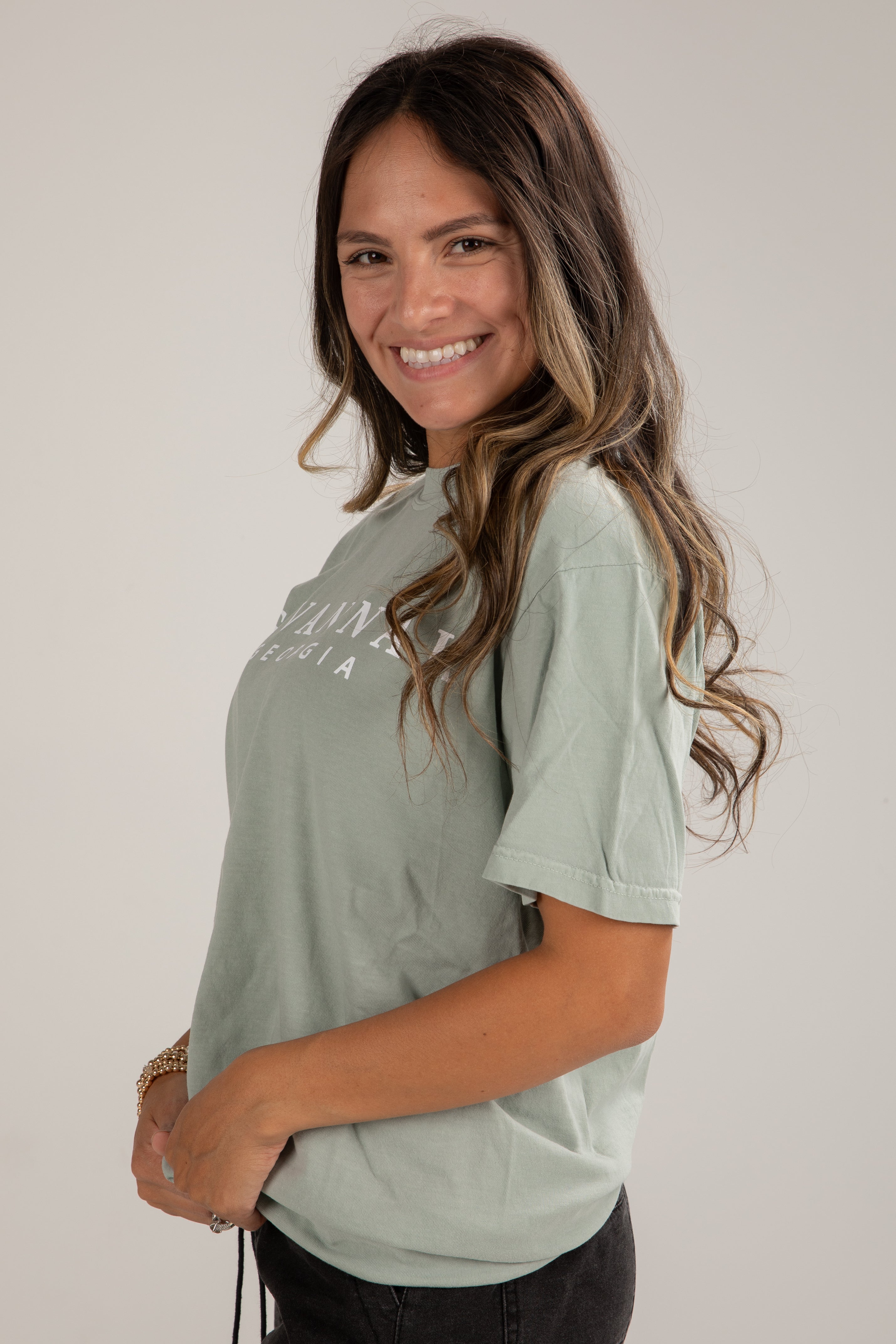 Woman wearing a light green t-shirt with text on a plain background