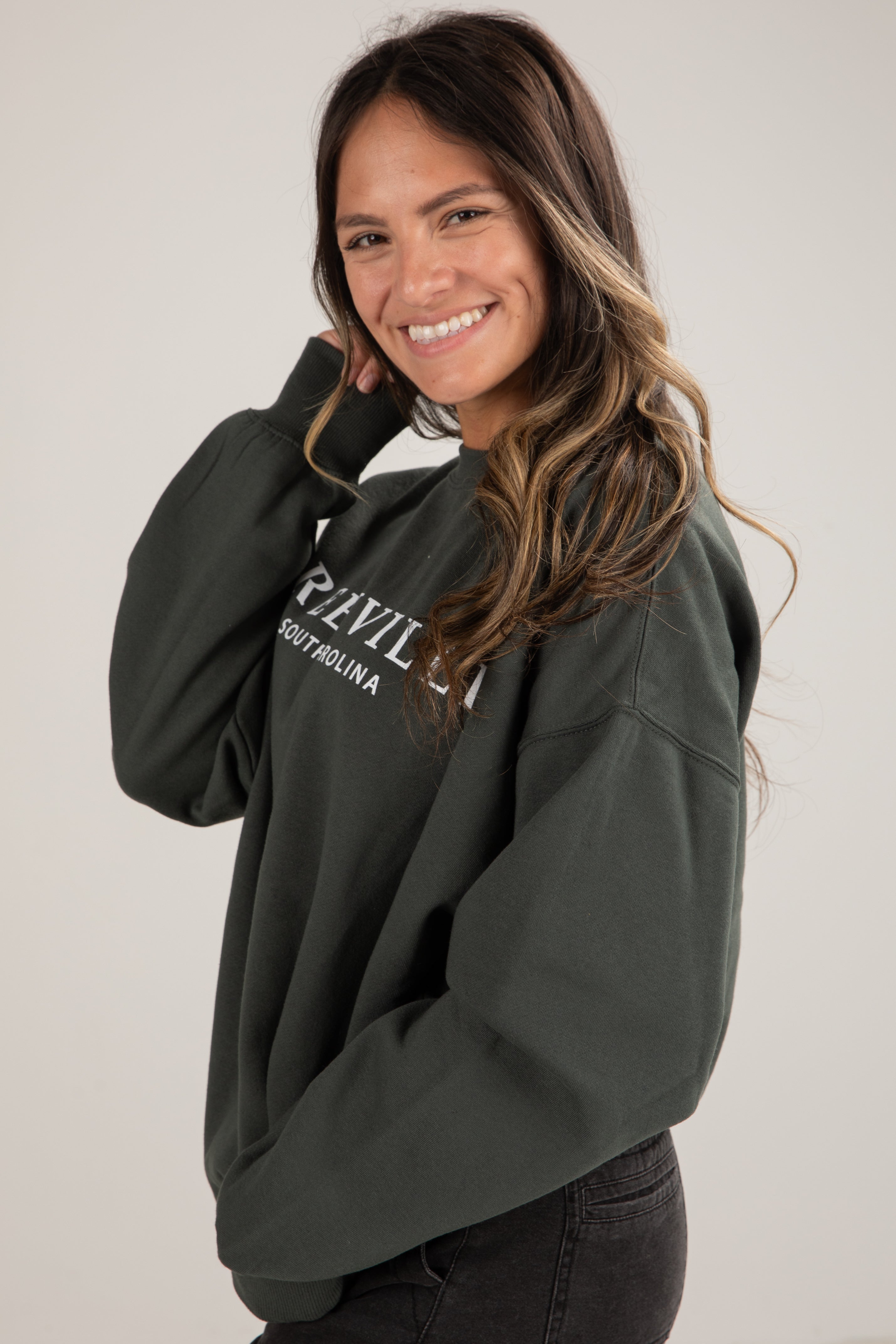 Woman wearing a dark green hoodie with text on a plain background