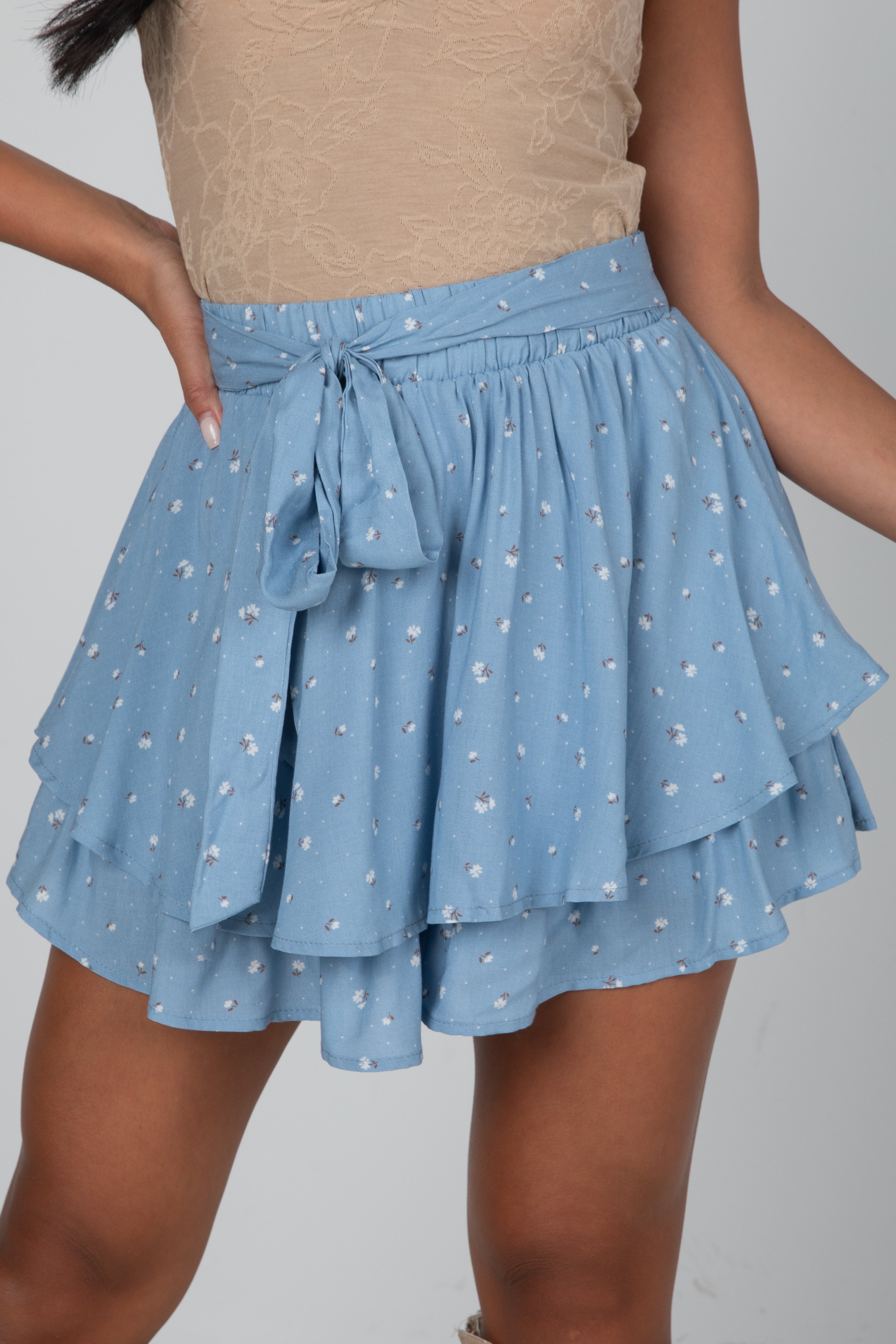 Blue tiered skirt with white floral pattern worn by a person on a gray background