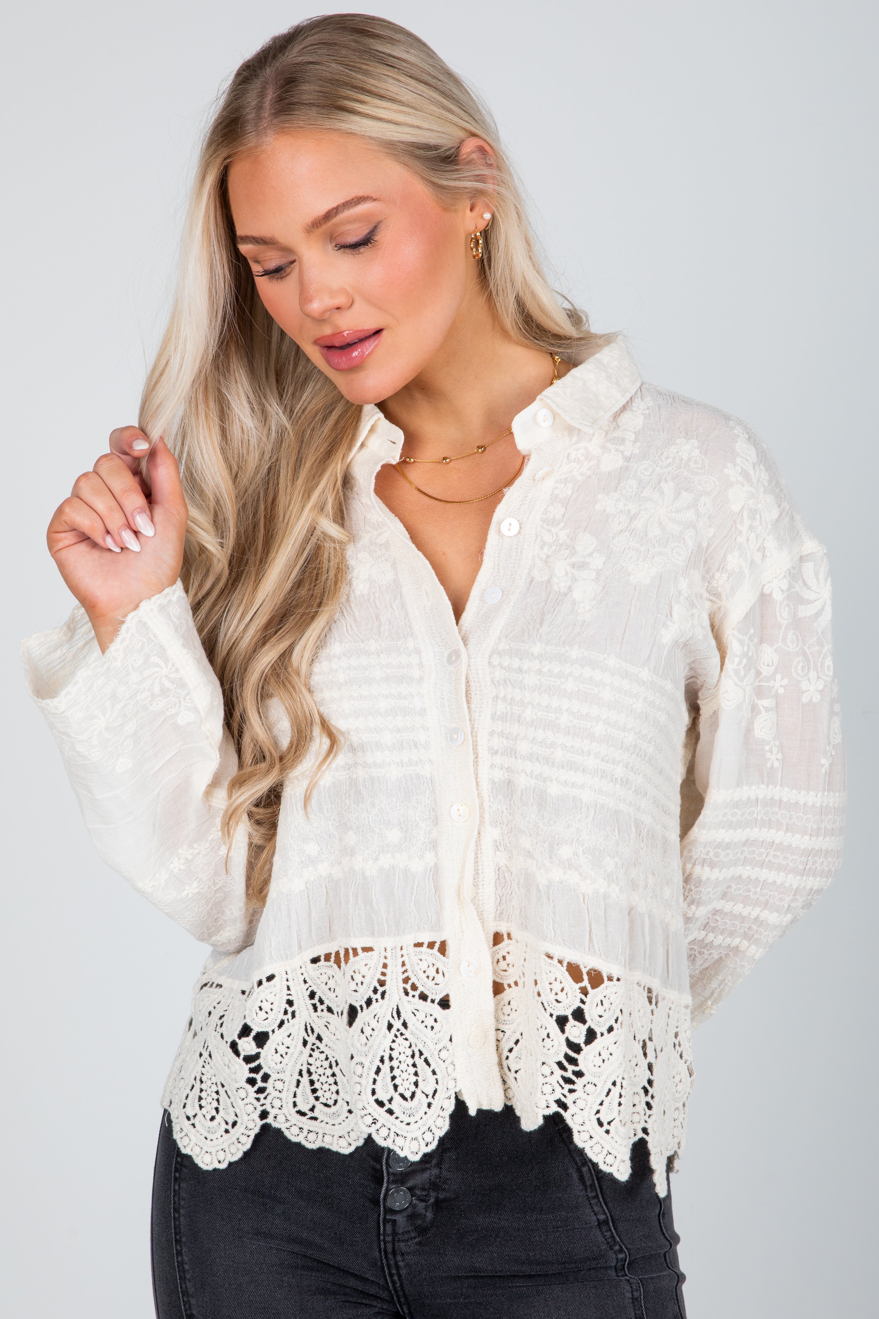 Woman wearing a white lace-trimmed blouse against a plain background