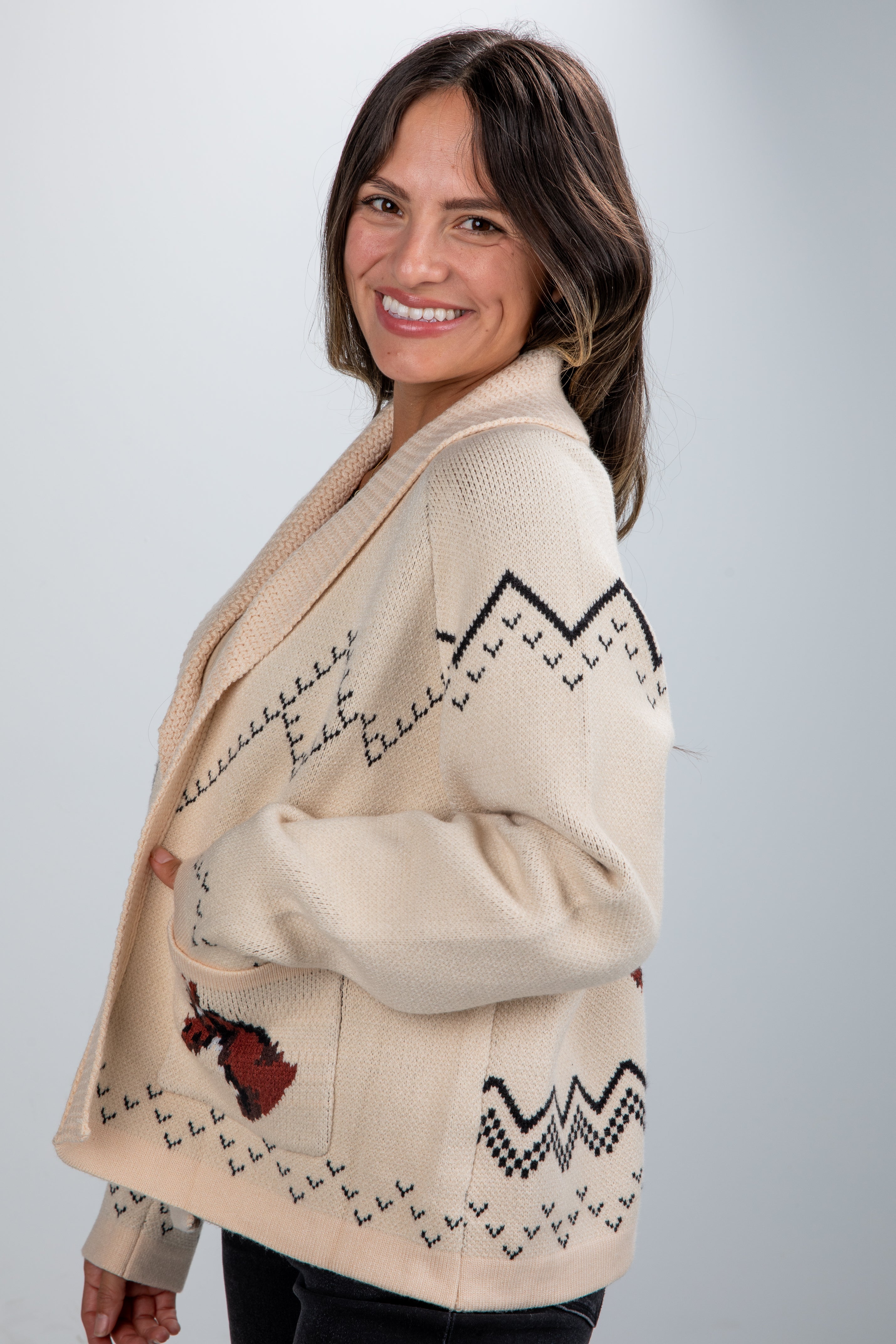Woman wearing a beige patterned cardigan on a light gray background