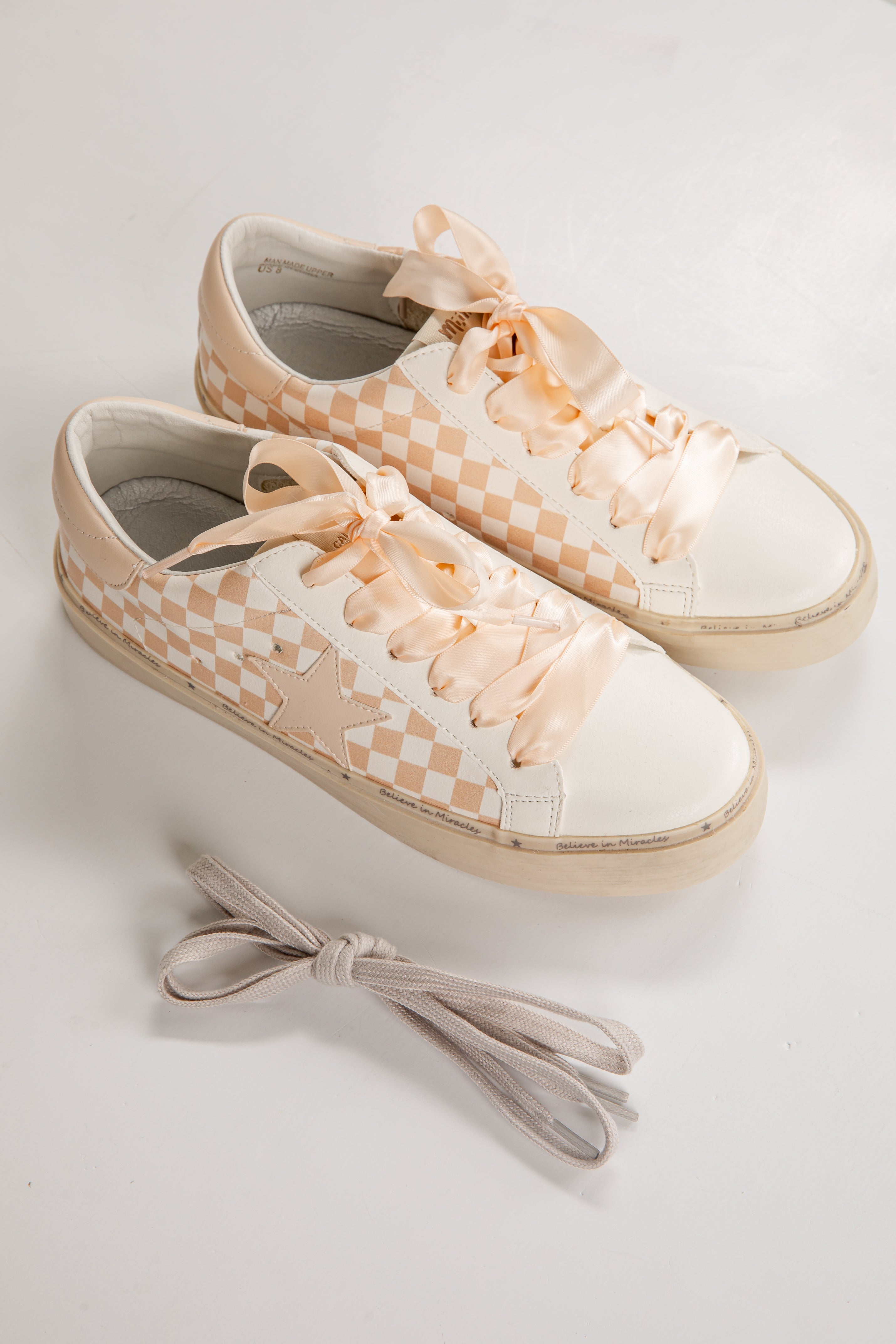 Pair of checkered sneakers with beige laces on a light background