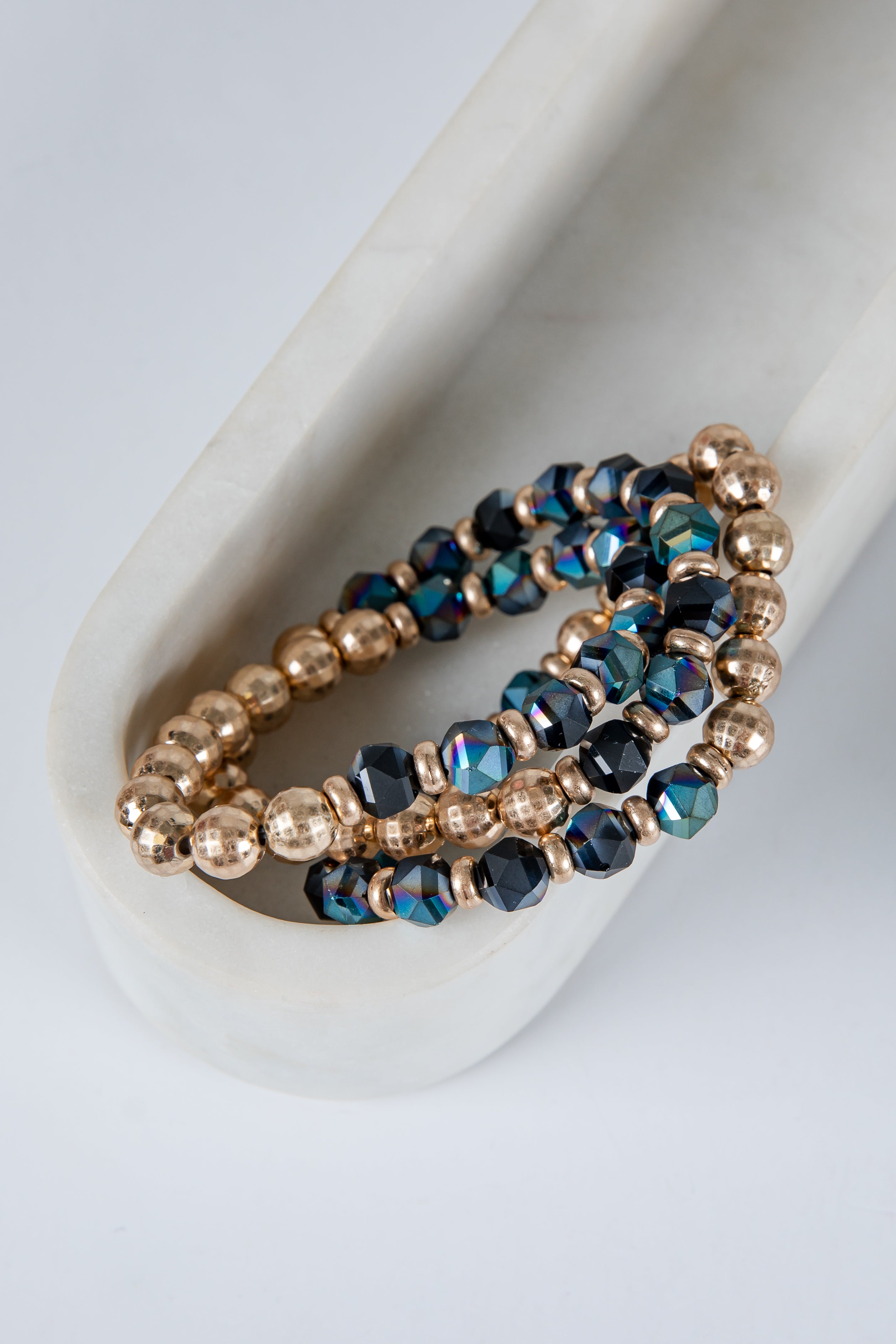 Set of beaded bracelets with gold and blue beads on a white surface