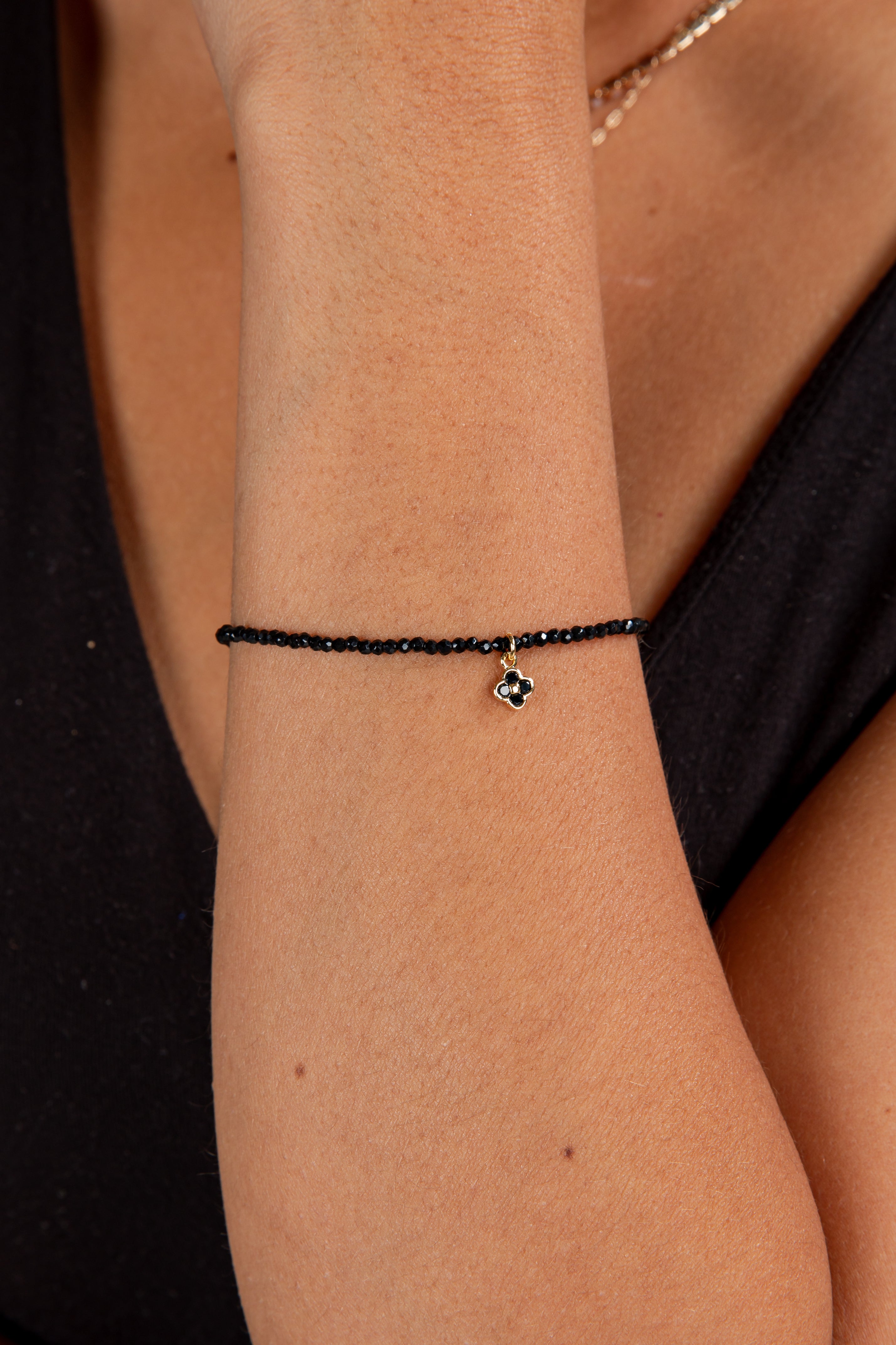 Black beaded bracelet on a wrist with a blurred background
