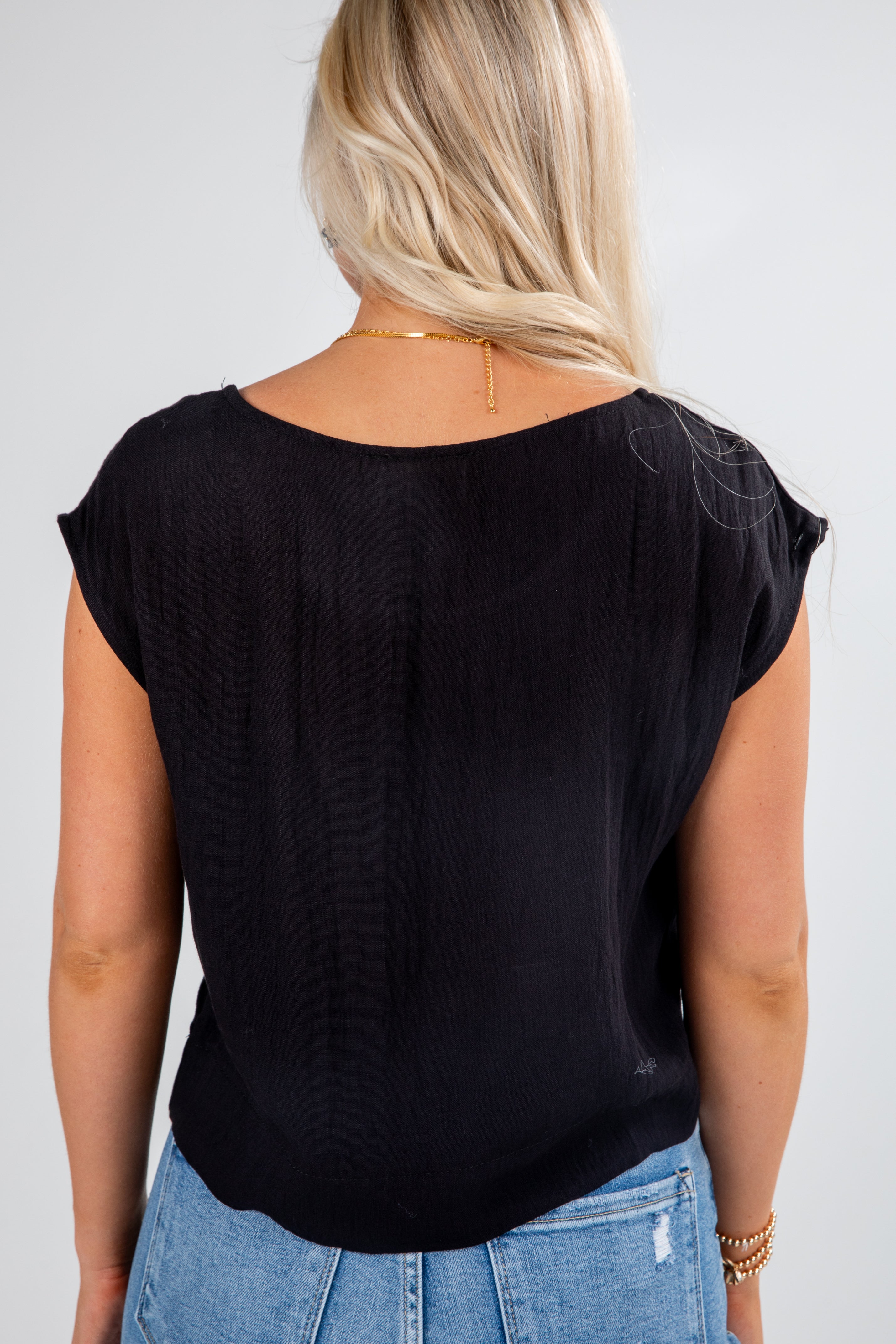 Person wearing a black top and blue jeans on a plain background