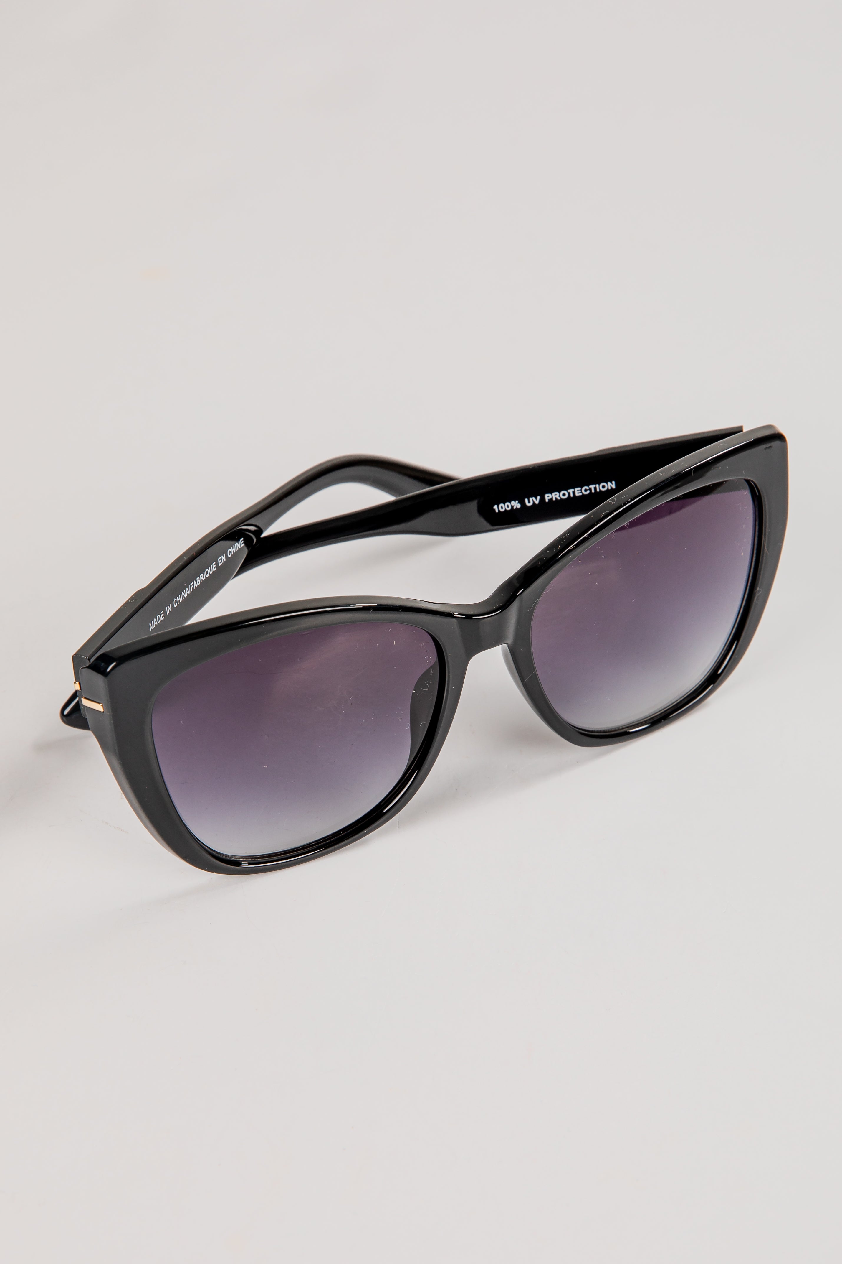Black sunglasses with dark lenses on a light gray background