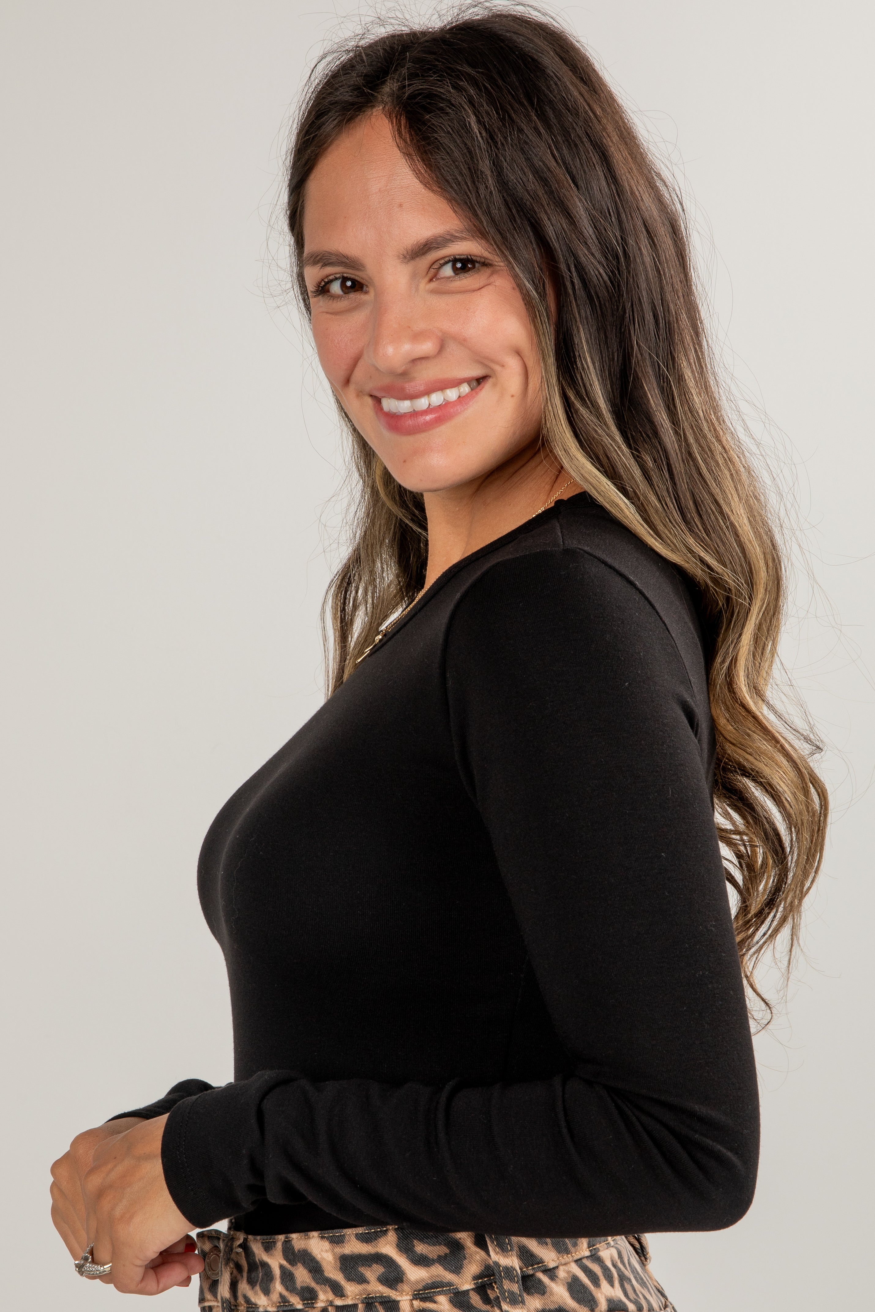 Woman wearing a black long-sleeve top with a plain background
