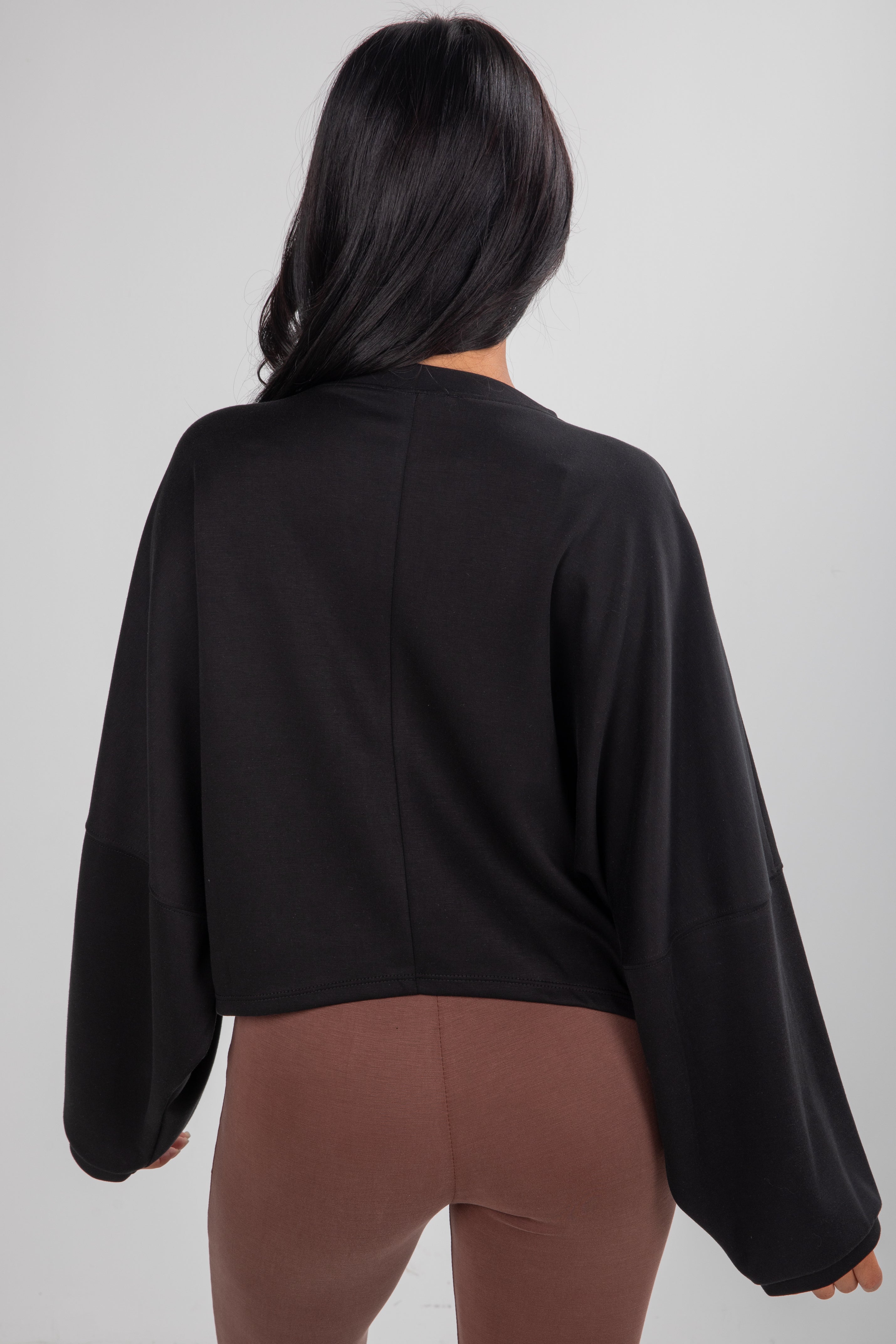 Person wearing a black top and brown pants on a plain background