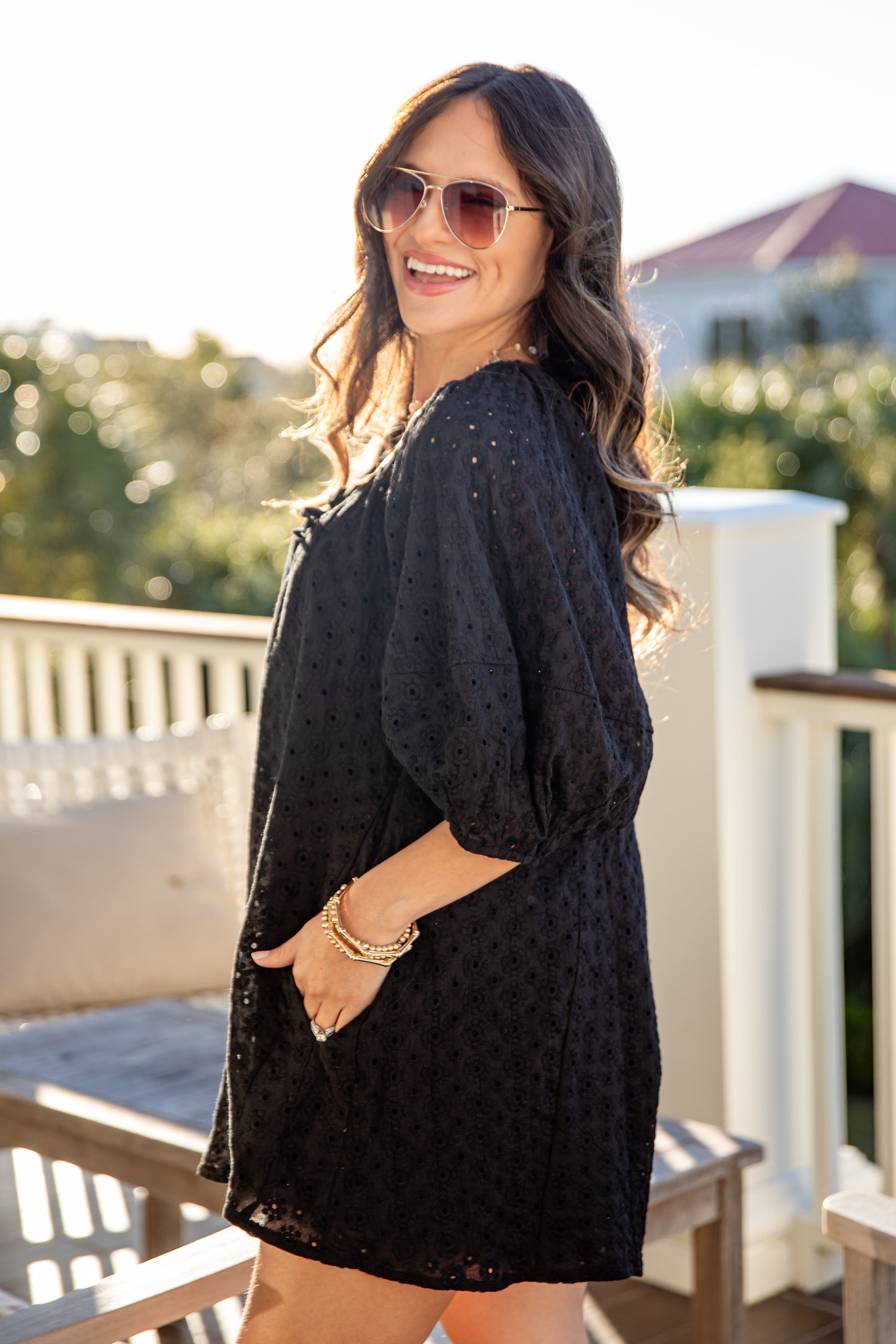 Woman wearing a black dress on a balcony with a blurred background