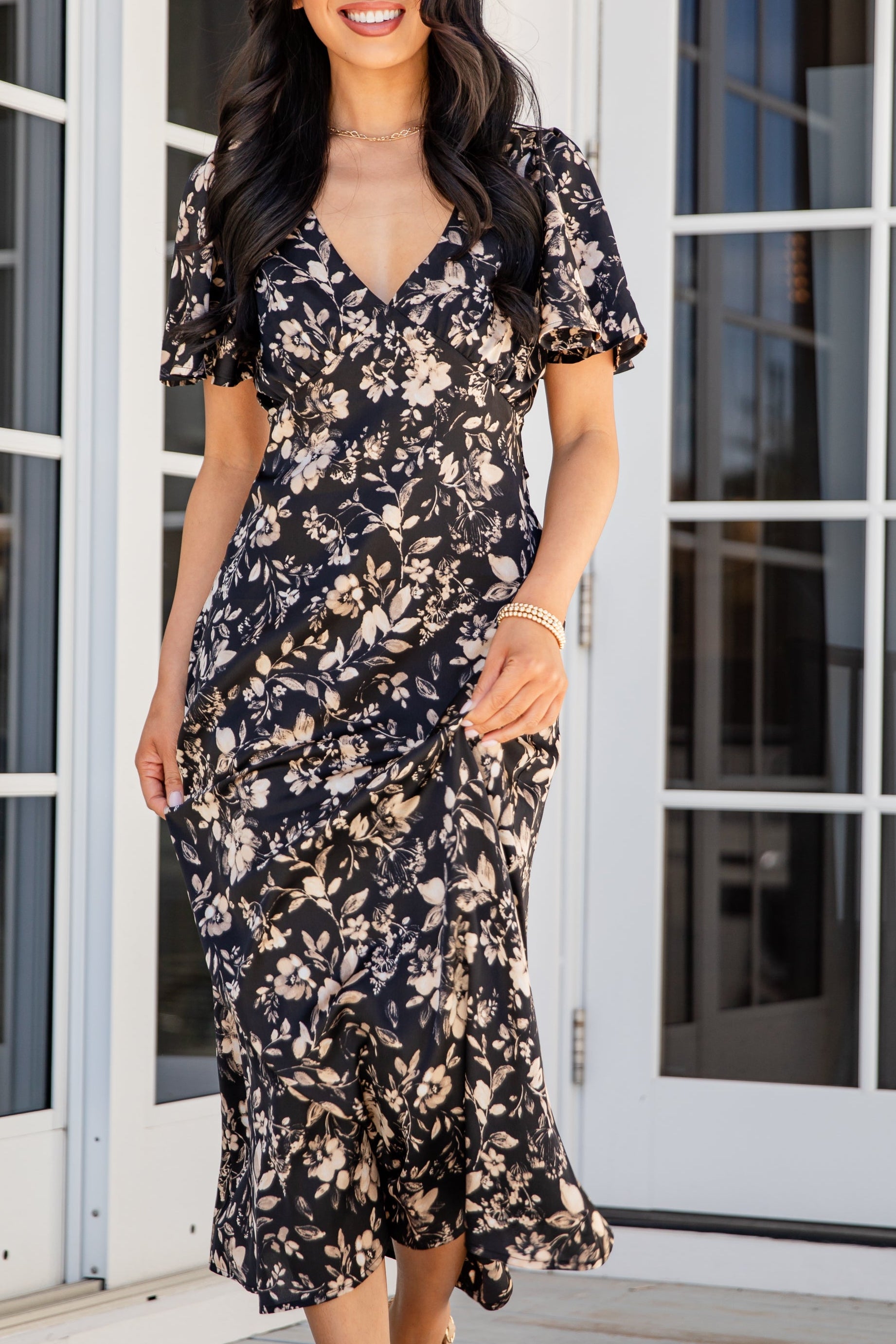 Woman in a floral dress standing in front of glass doors.