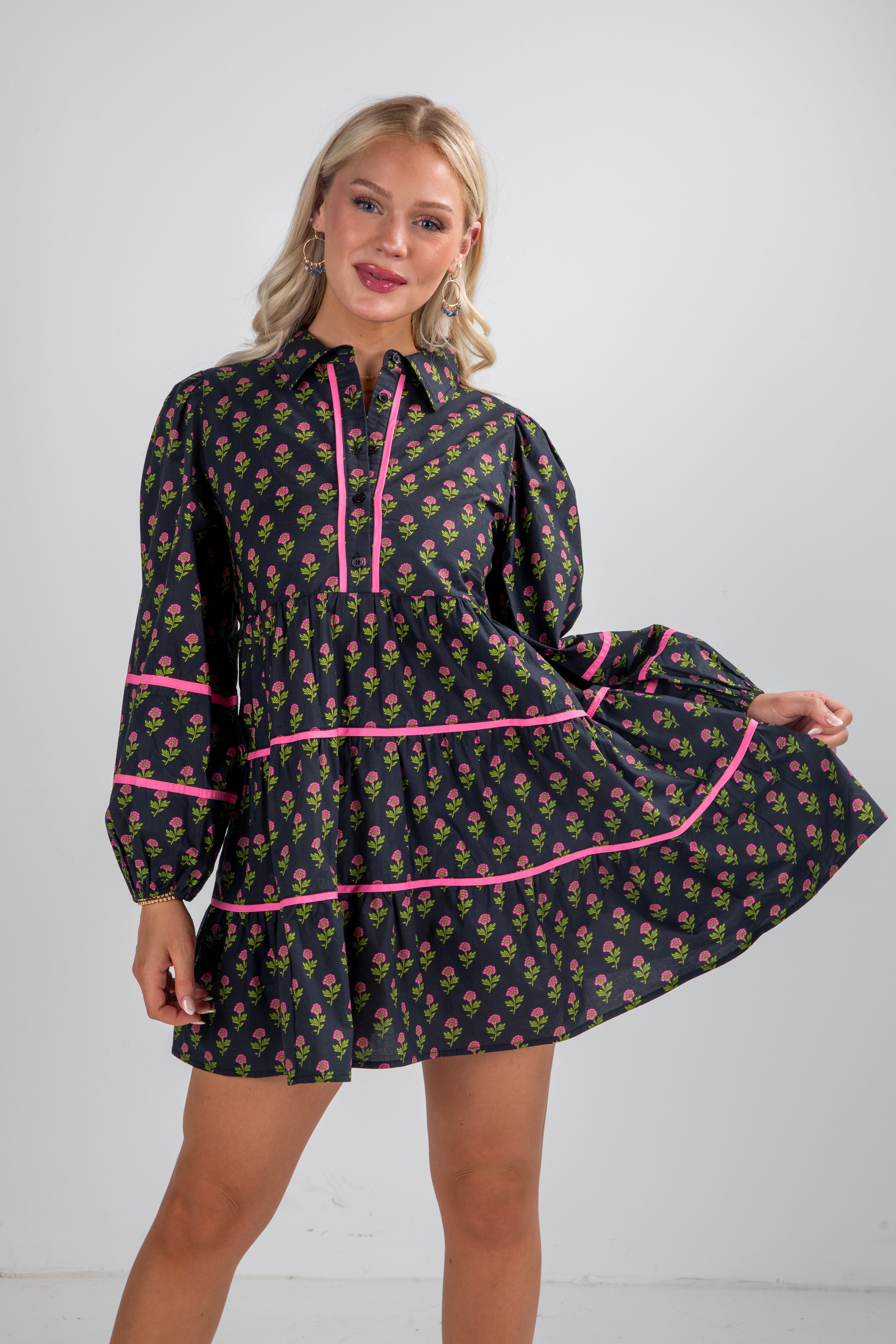 Woman wearing a black floral dress with pink accents on a white background