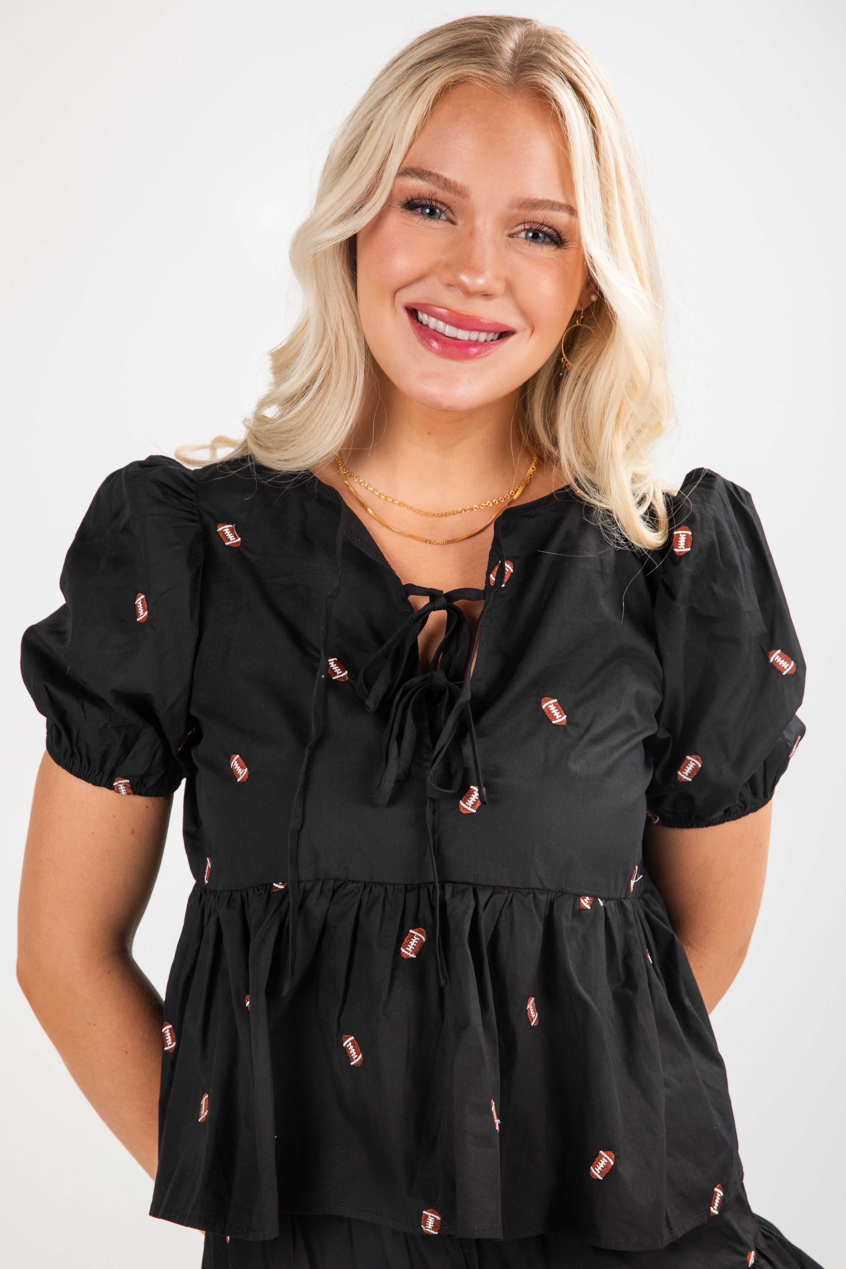 Woman wearing a black blouse with small red patterns on a white background