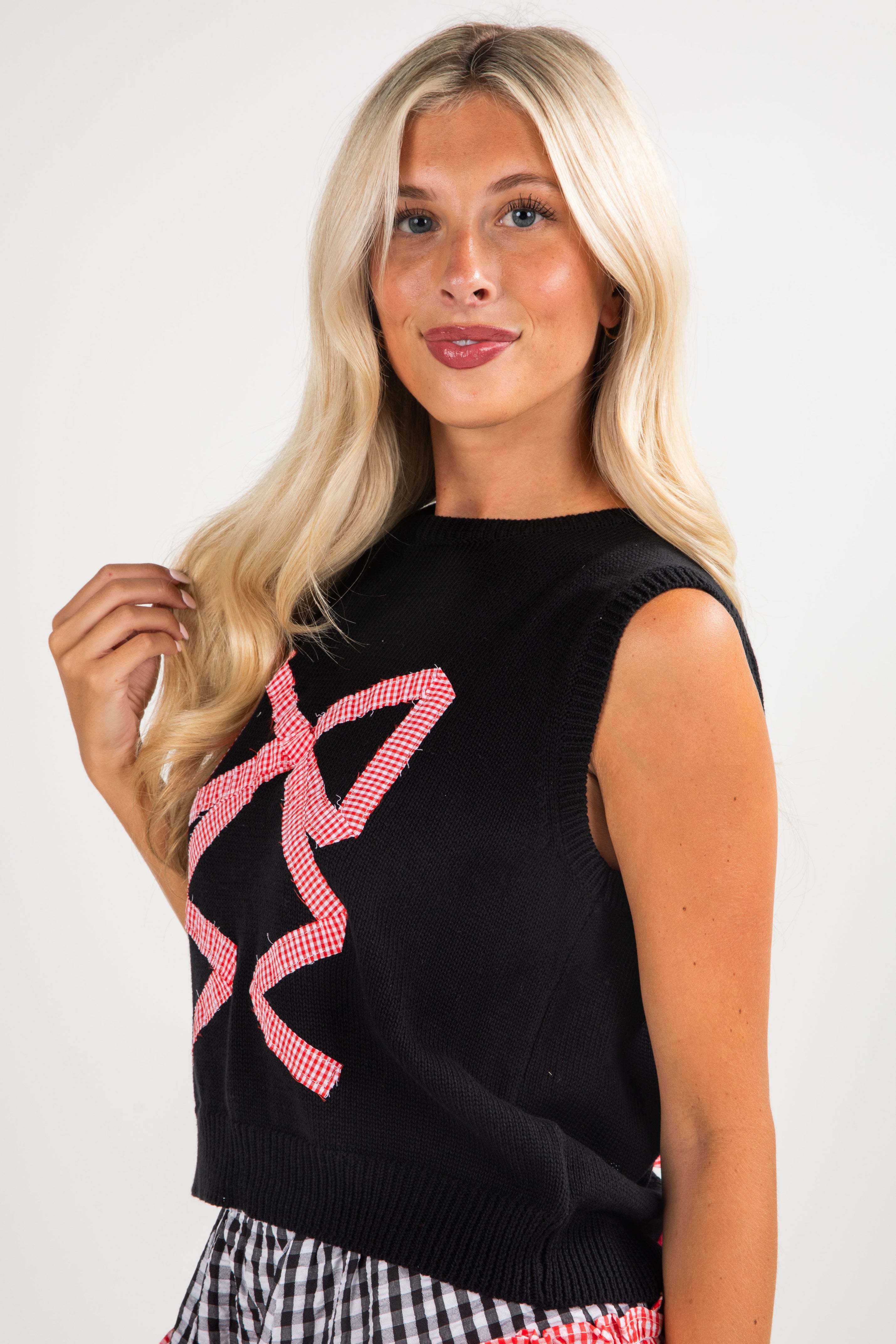 Woman wearing a black sleeveless top with pink designs against a white background