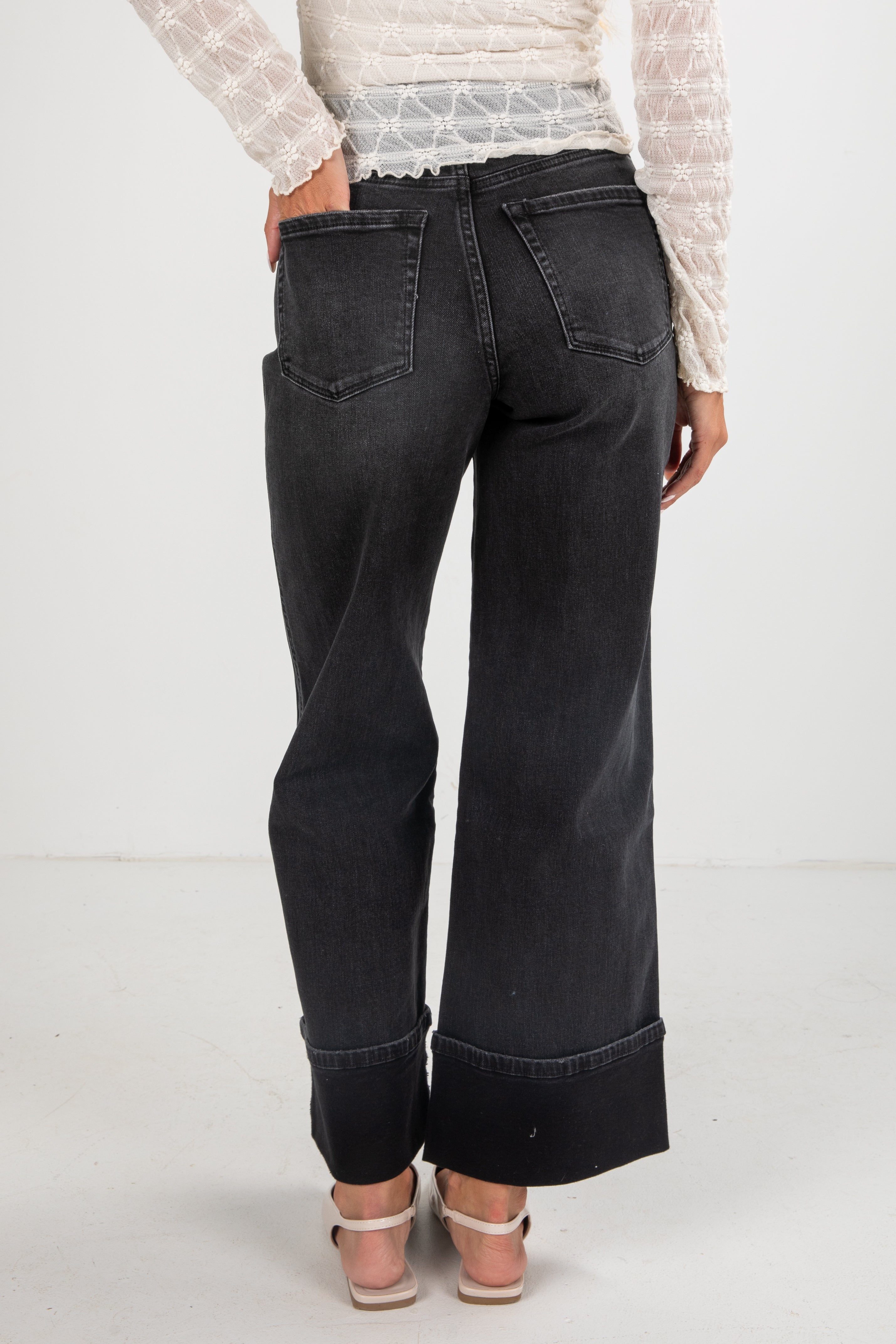 Person wearing black wide-leg jeans on a white background