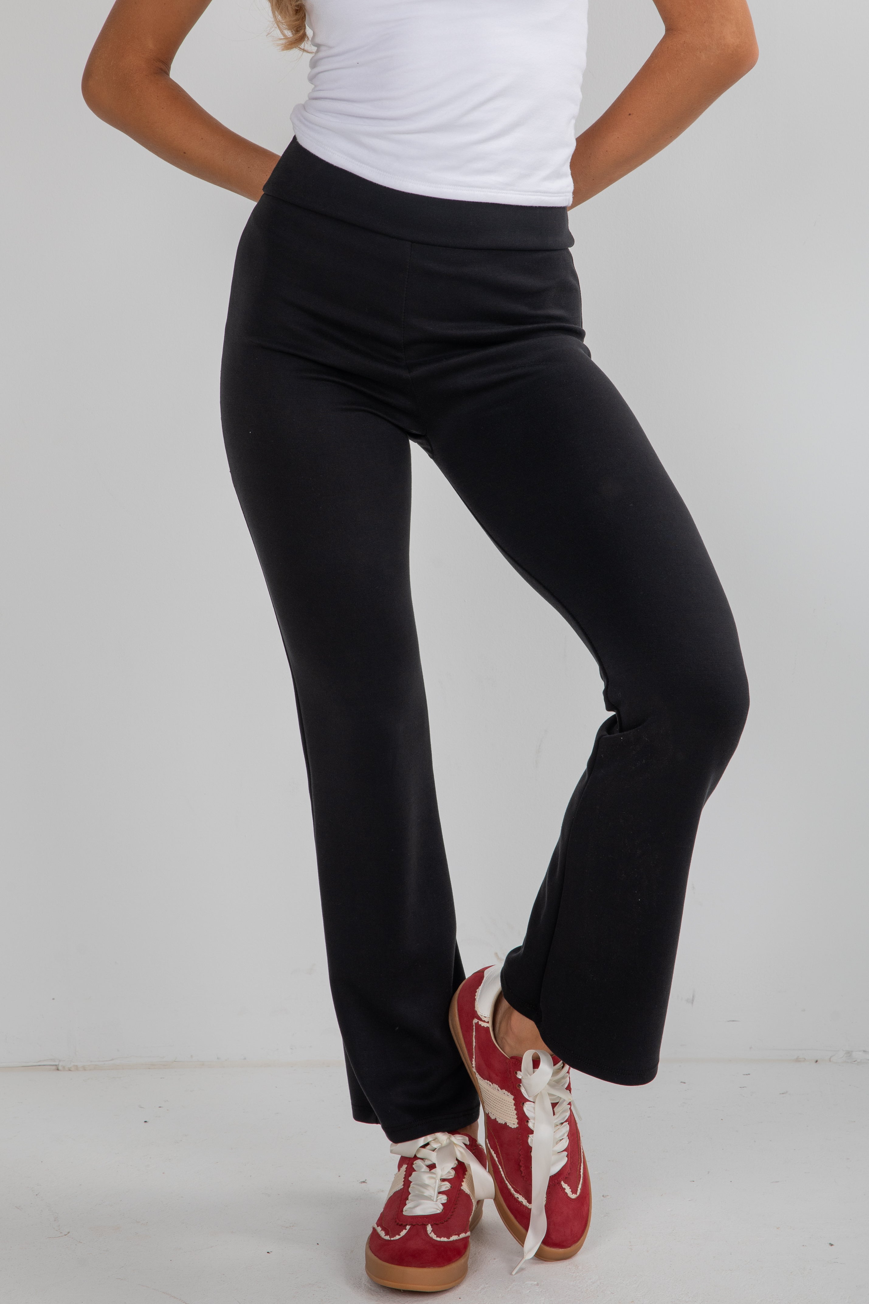 Person wearing black pants and red sneakers on a white background