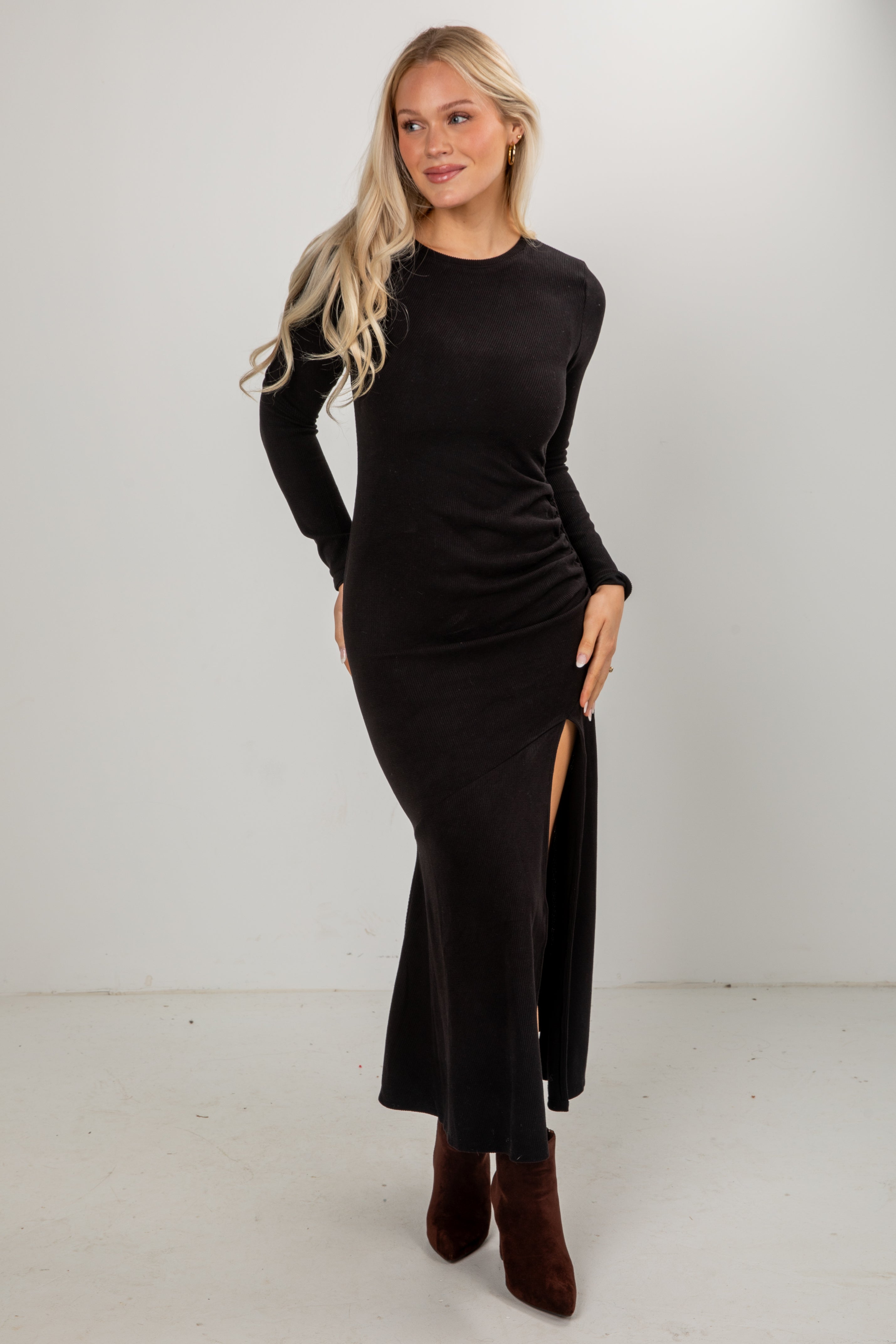 Woman wearing a black long-sleeve dress with a slit on a white background