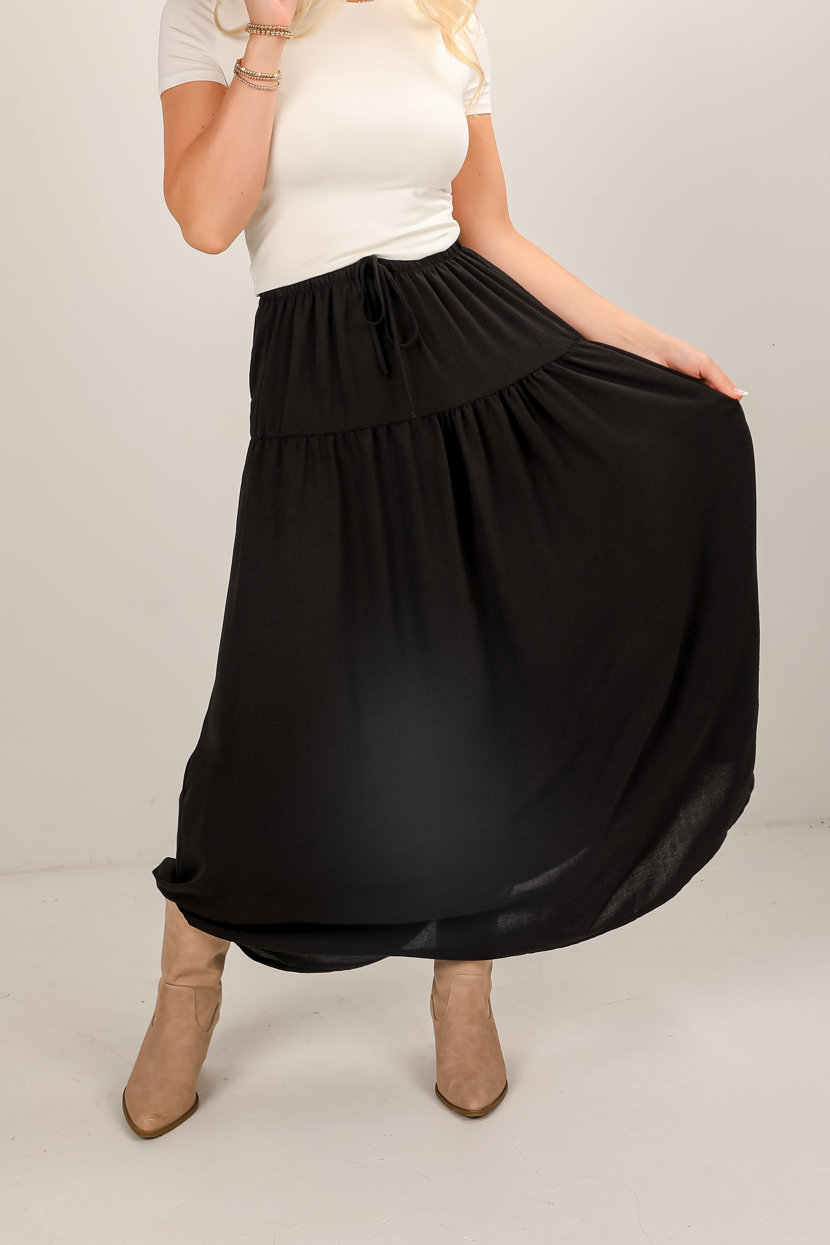 Person wearing a black skirt and white top on a plain background