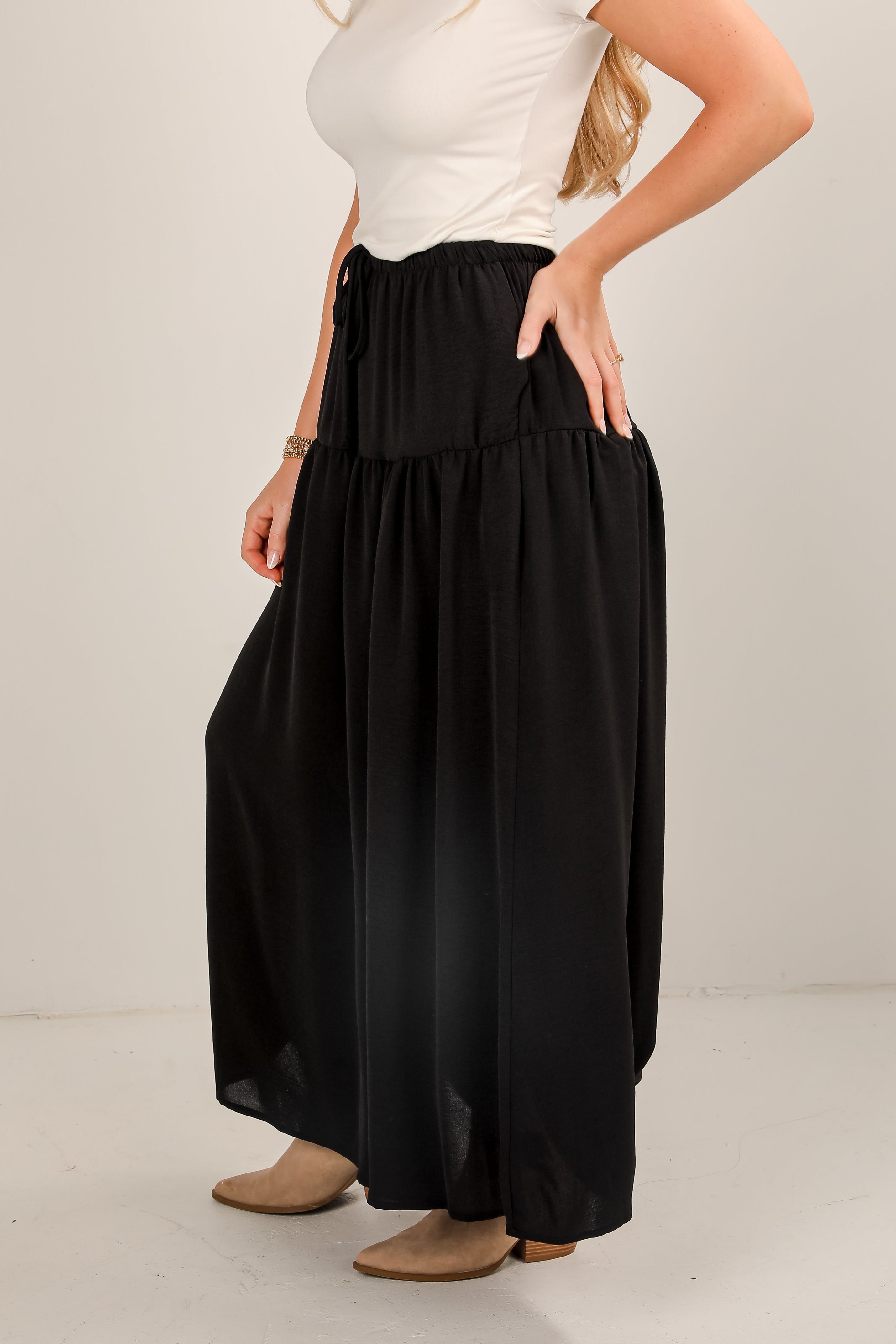 Person wearing a white top and black wide-leg pants on a plain background