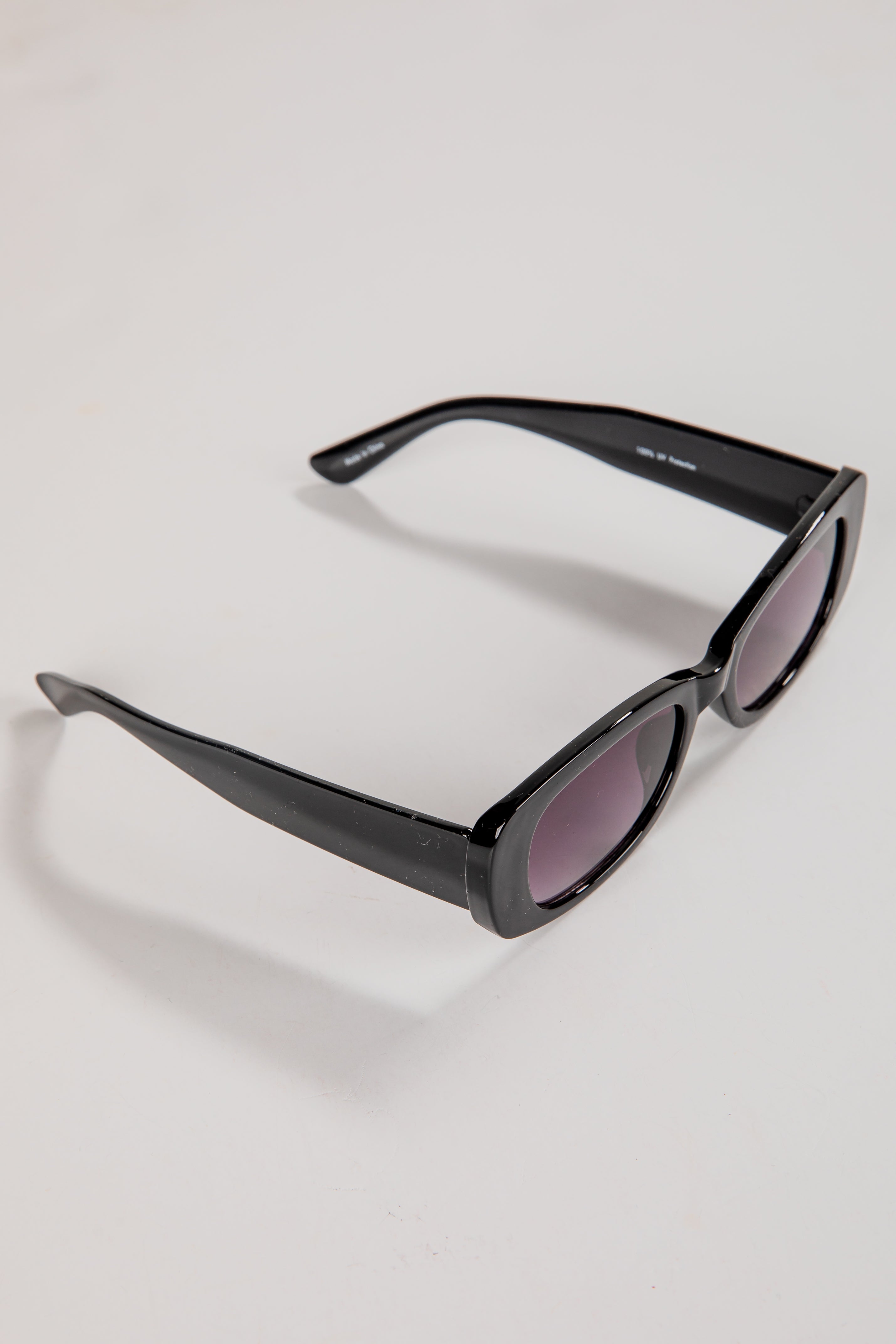 Black sunglasses with purple lenses on a light gray background