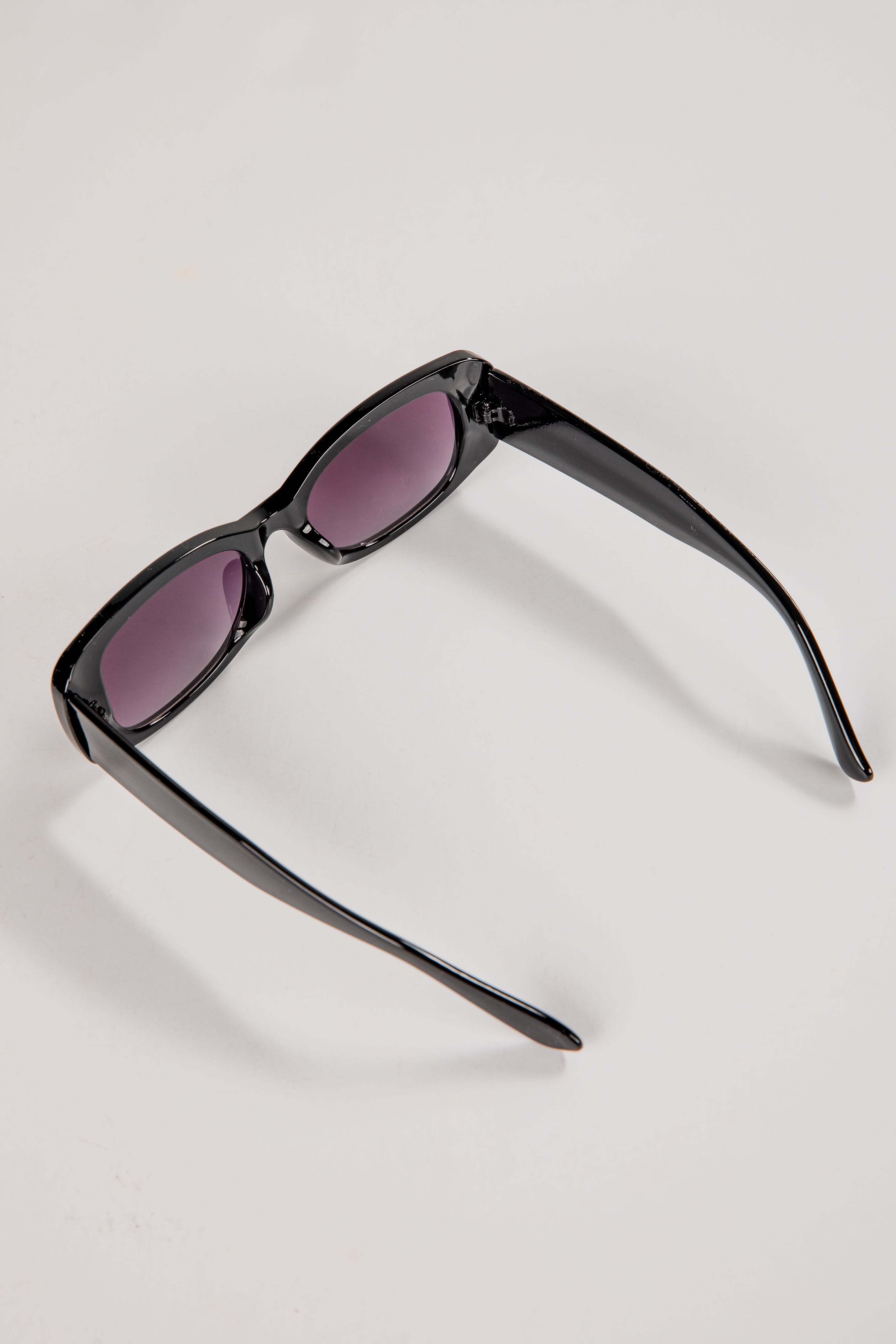 Black sunglasses with purple lenses on a light gray background