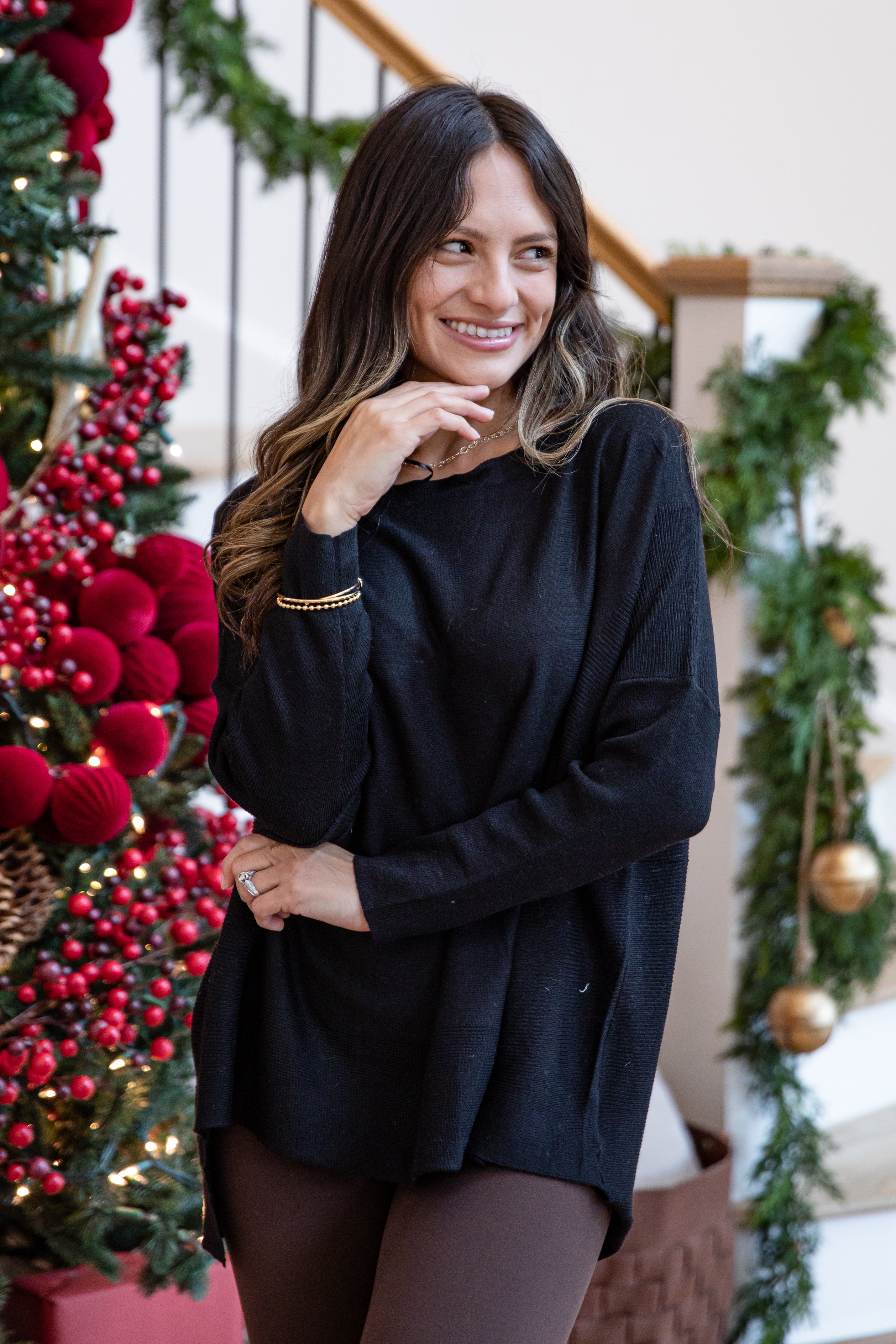 Woman in a black sweater standing in front of a decorated Christmas tree.