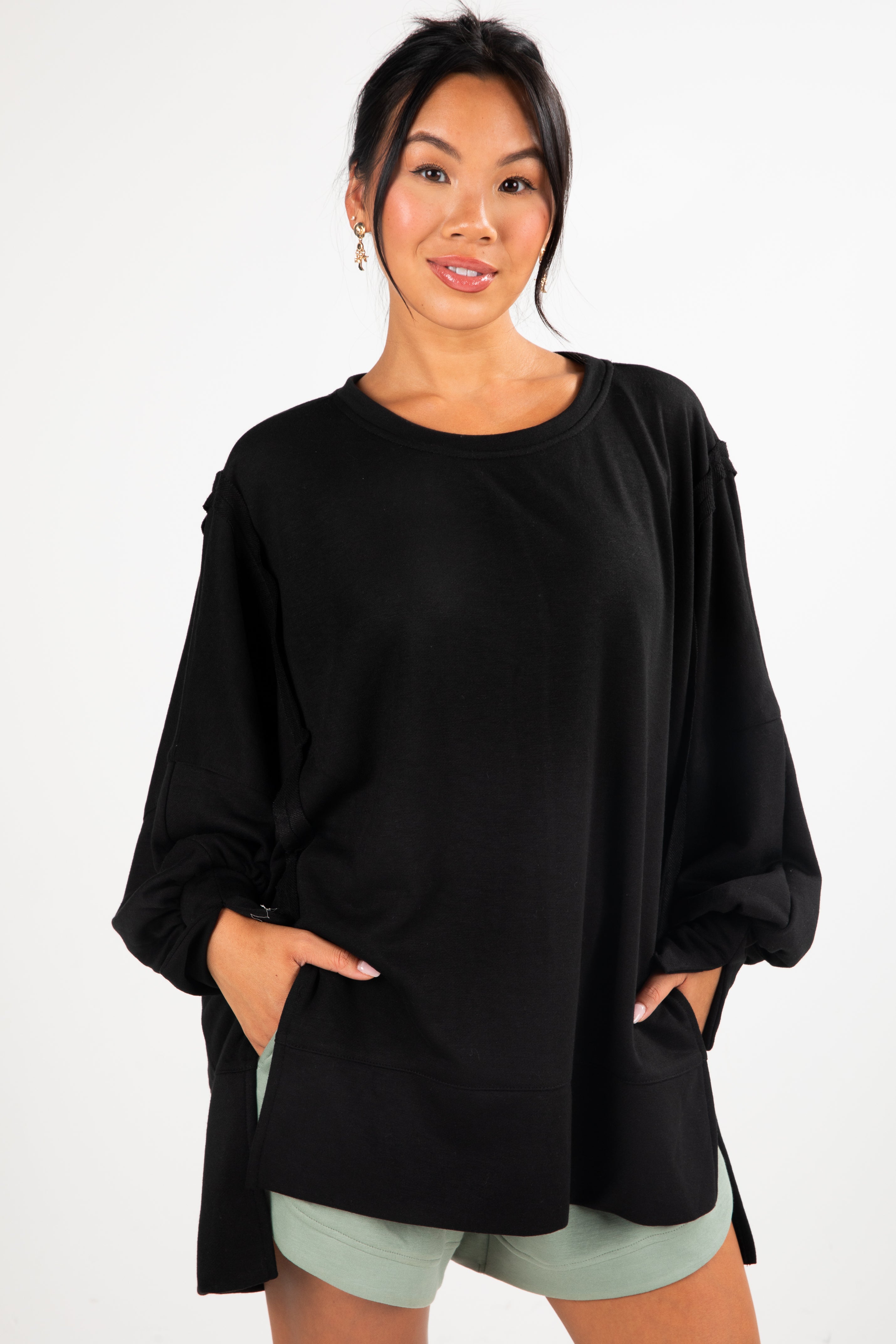 Woman wearing a black oversized top with a white background