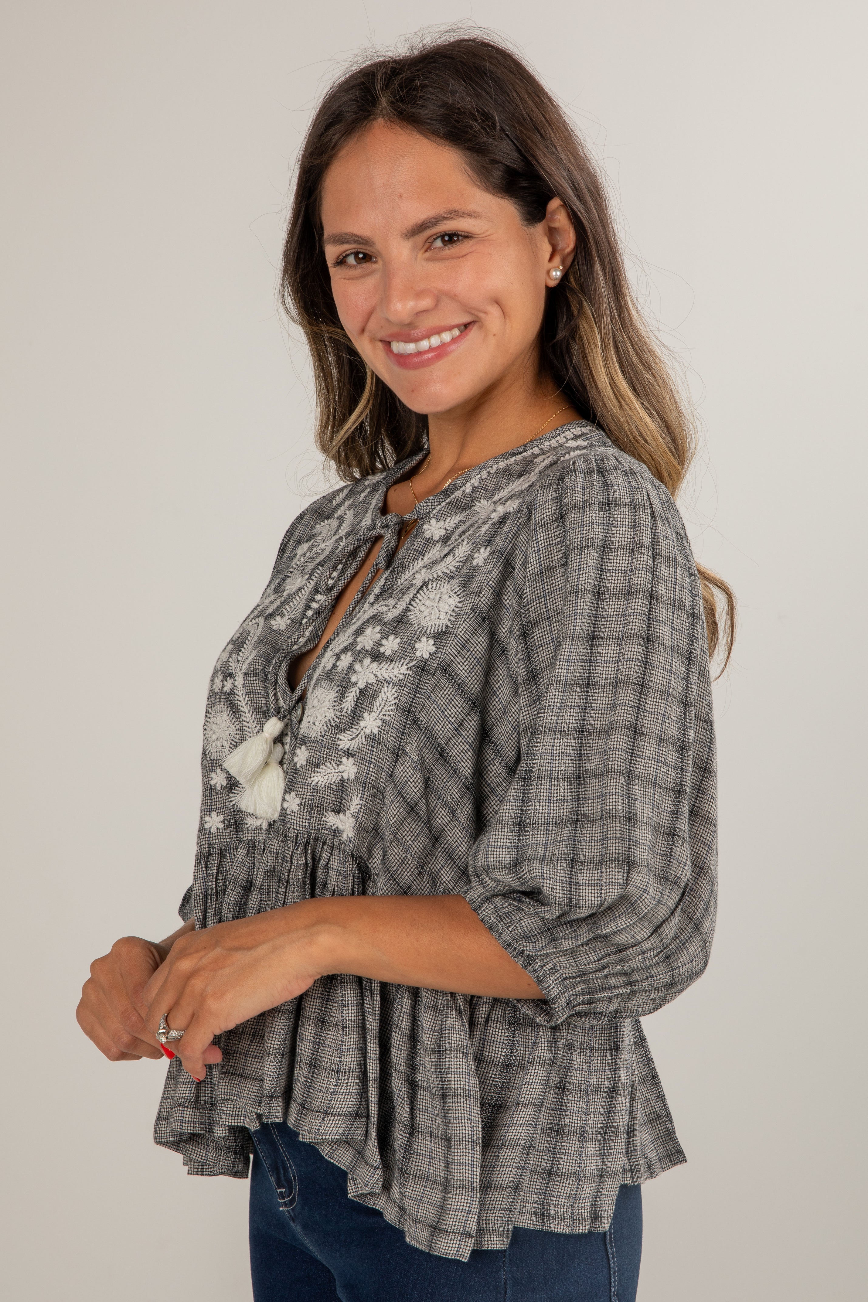 Woman wearing a plaid blouse with floral details on a plain background