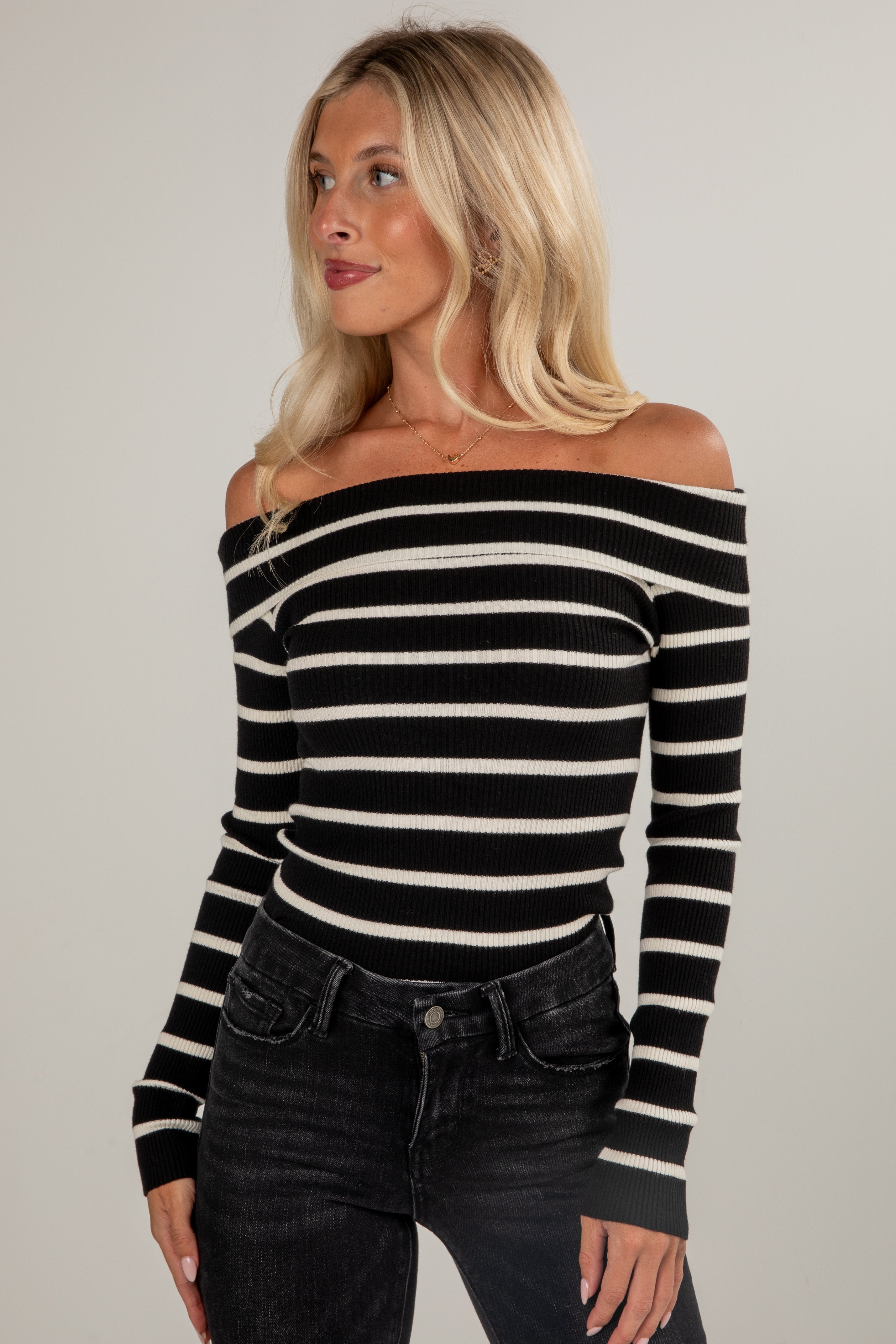 Woman wearing a black and white striped long-sleeve top against a plain background