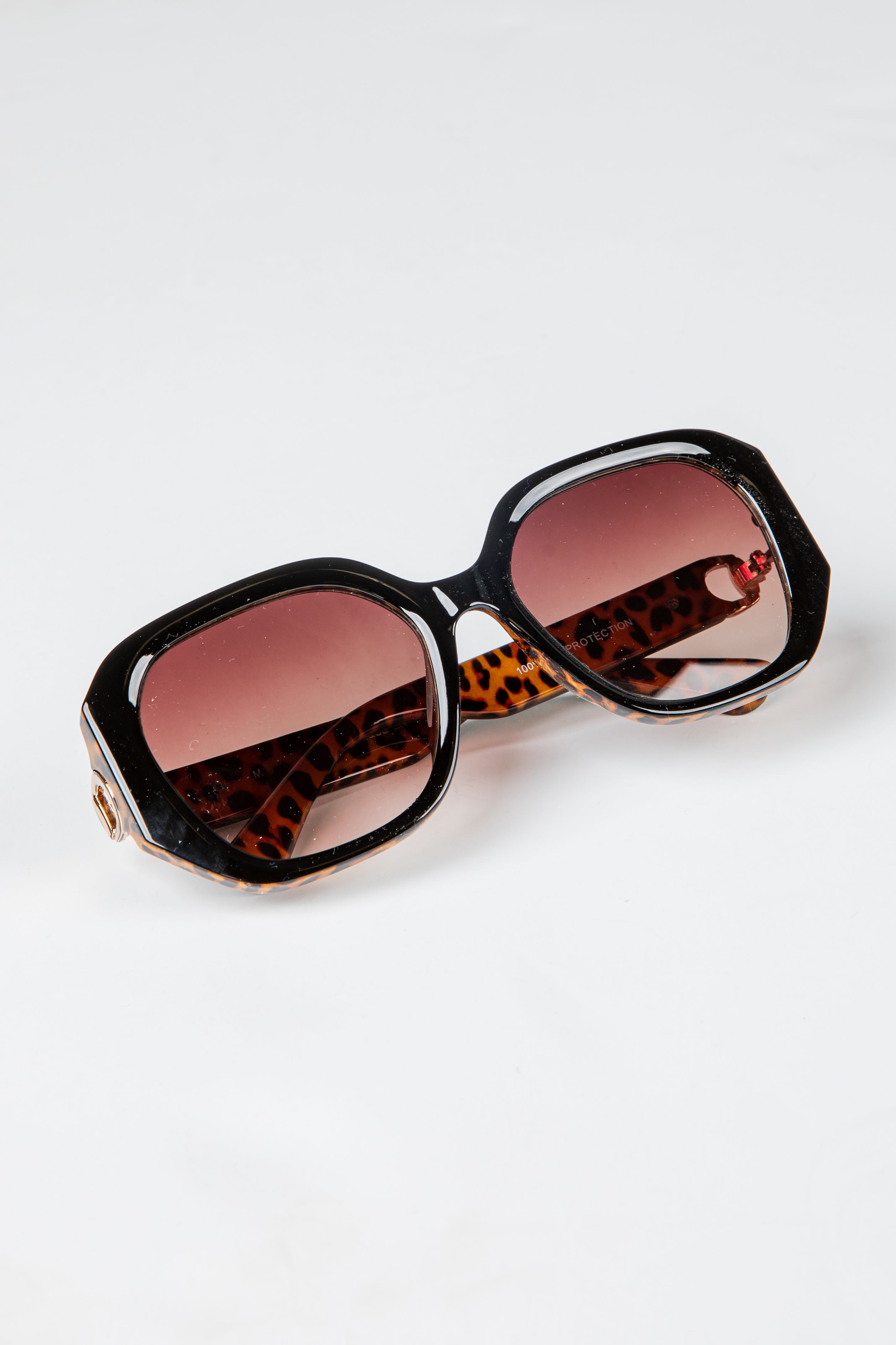 Sunglasses with leopard print frame and red lenses on a white background