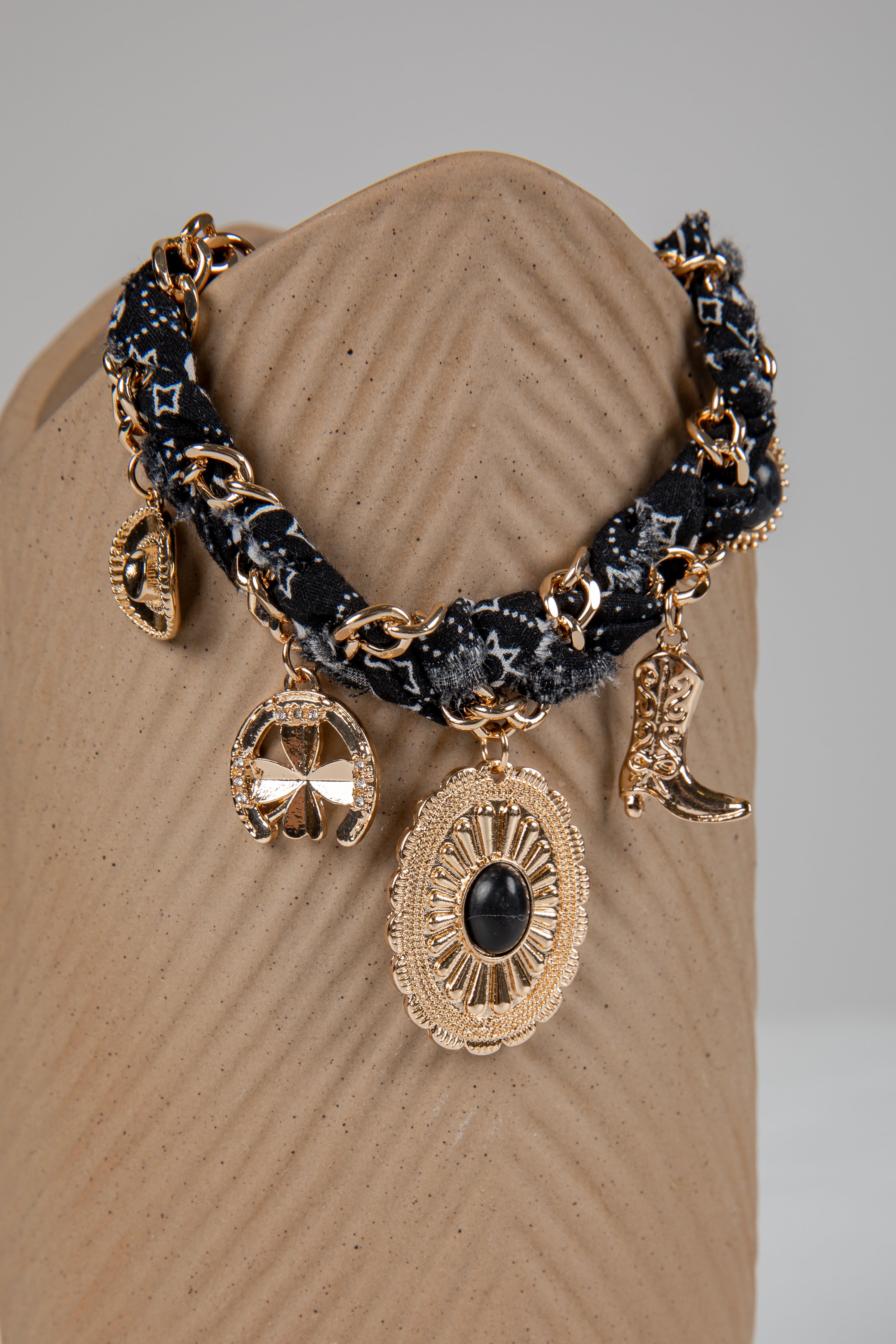 Decorative bracelet with gold and black elements on a beige stand