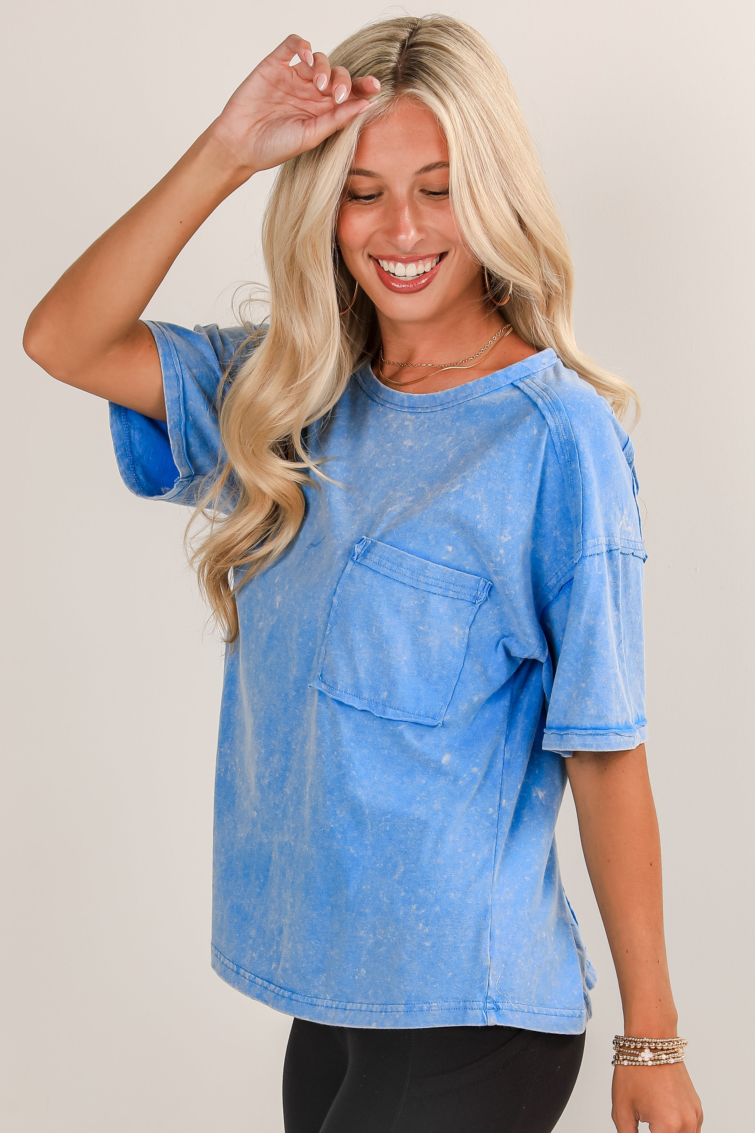 Woman wearing a blue distressed shirt with a neutral background