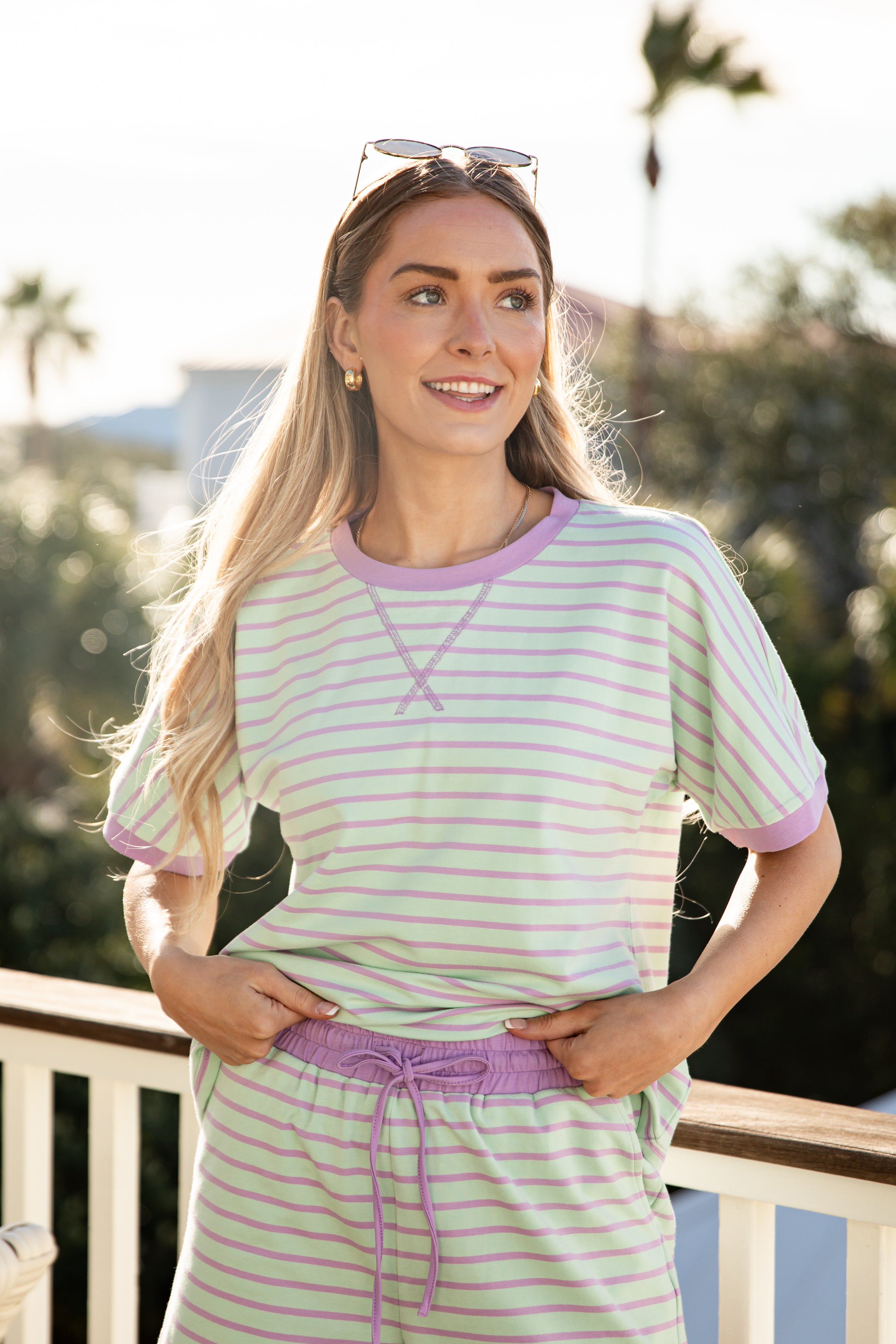 Woman wearing a striped shirt and pants with a blurred outdoor background