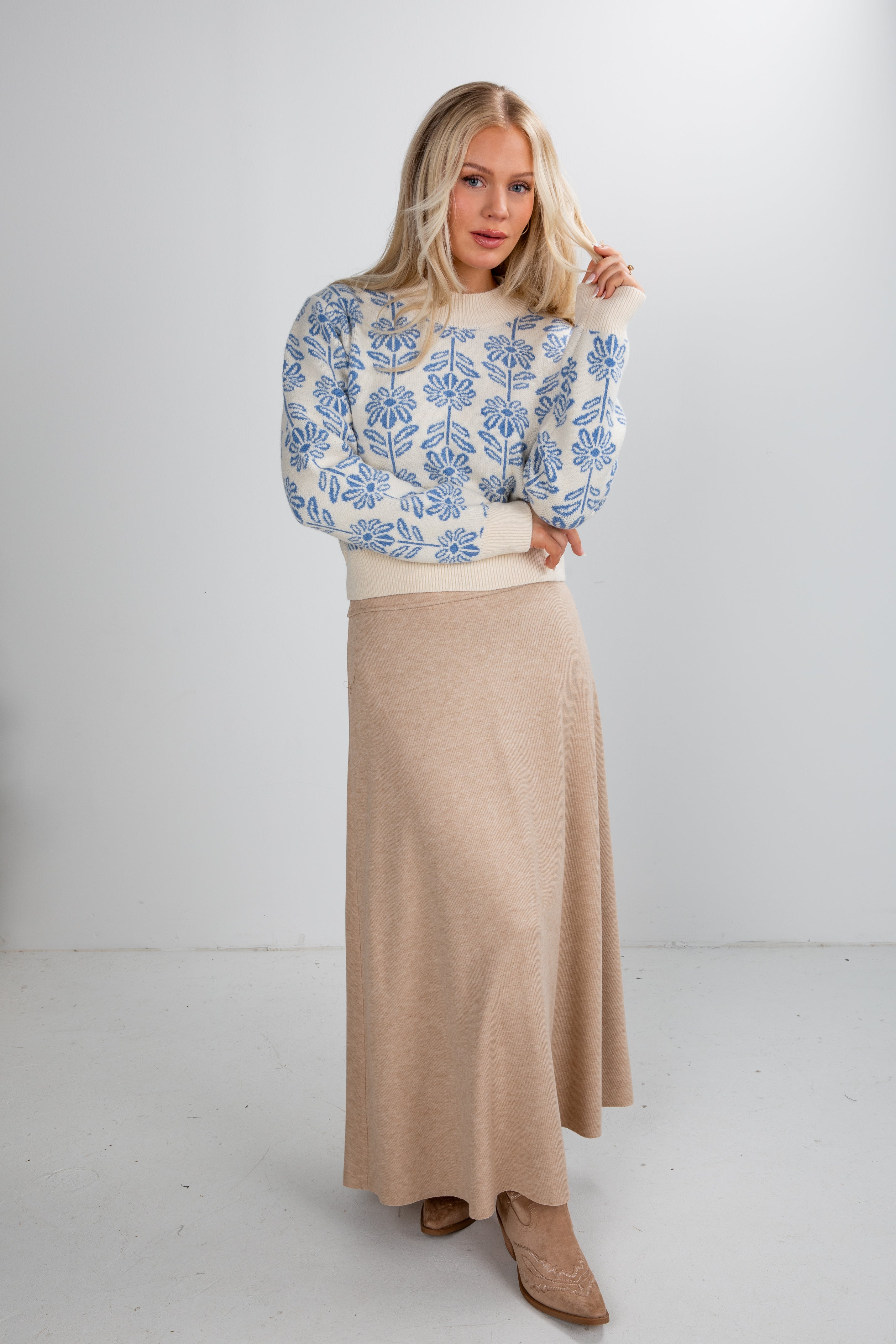 Woman wearing a floral sweater and beige skirt on a white background