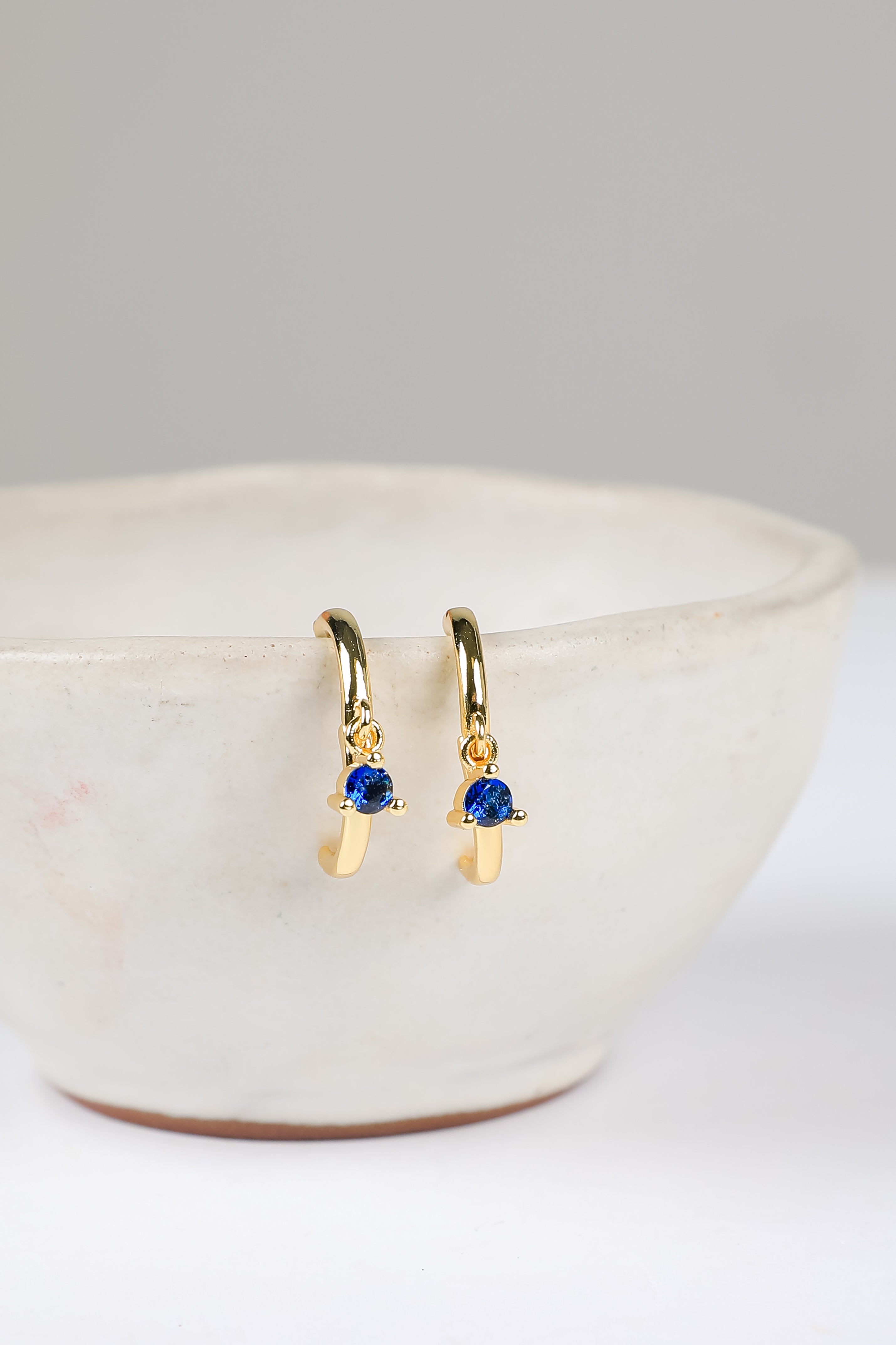 Gold earrings with blue gemstones on a white surface