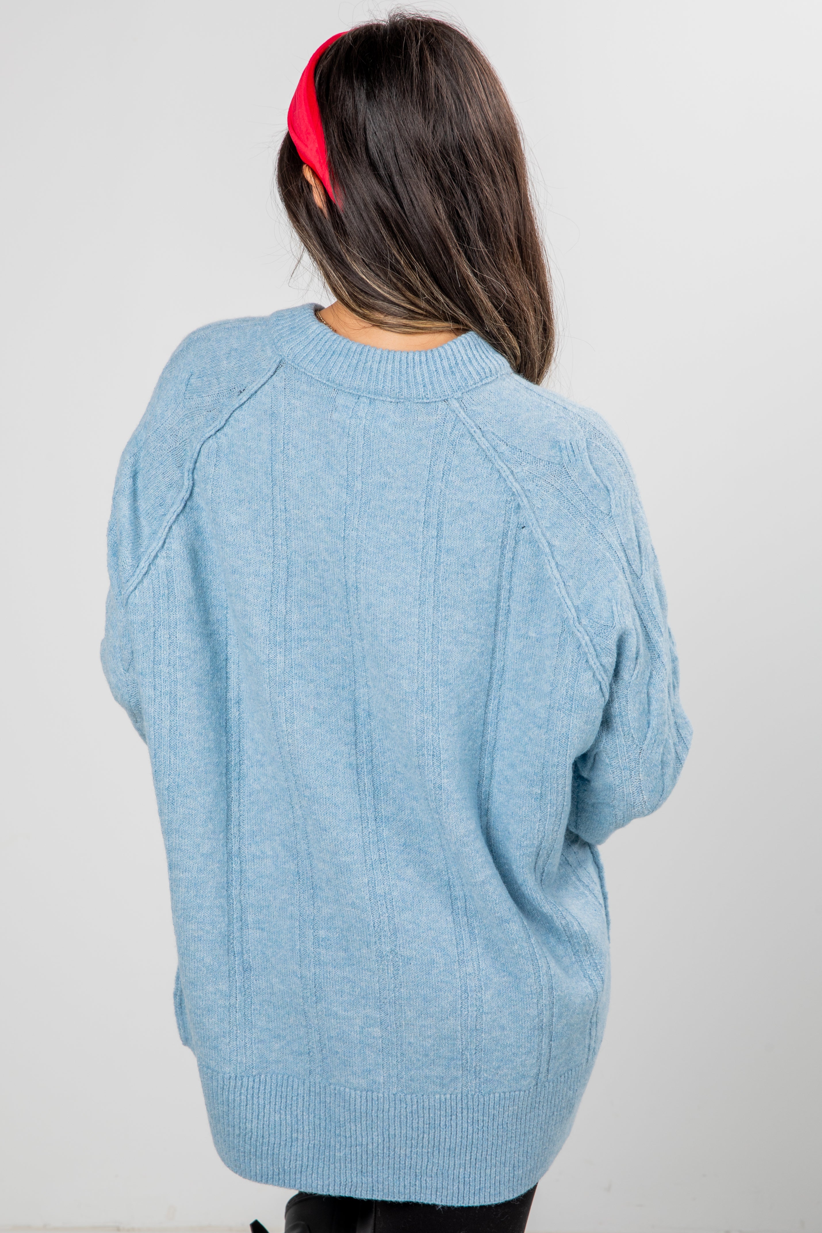 Person wearing a light blue sweater with a plain background